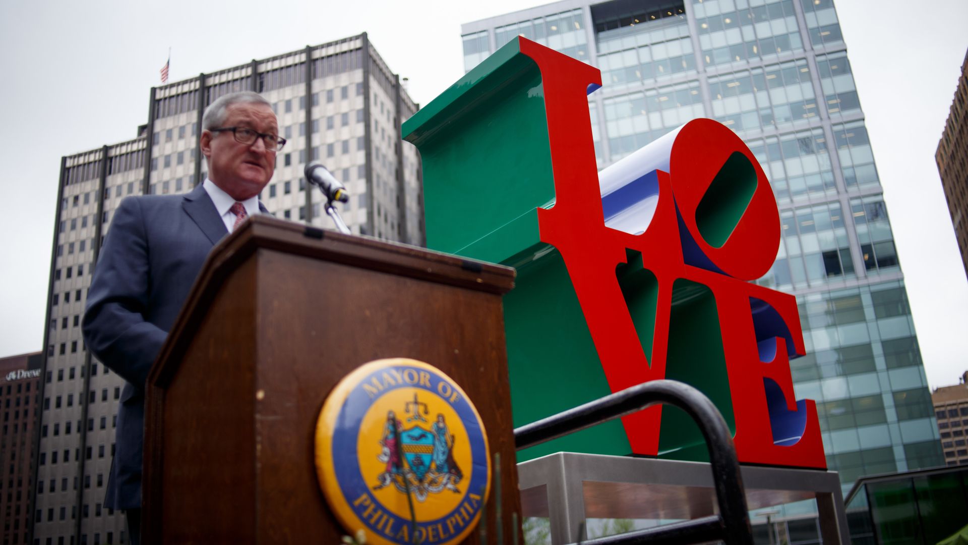 The Philadelphia mayor speaks at a podium with the red sculpture of "LOVE" in the background