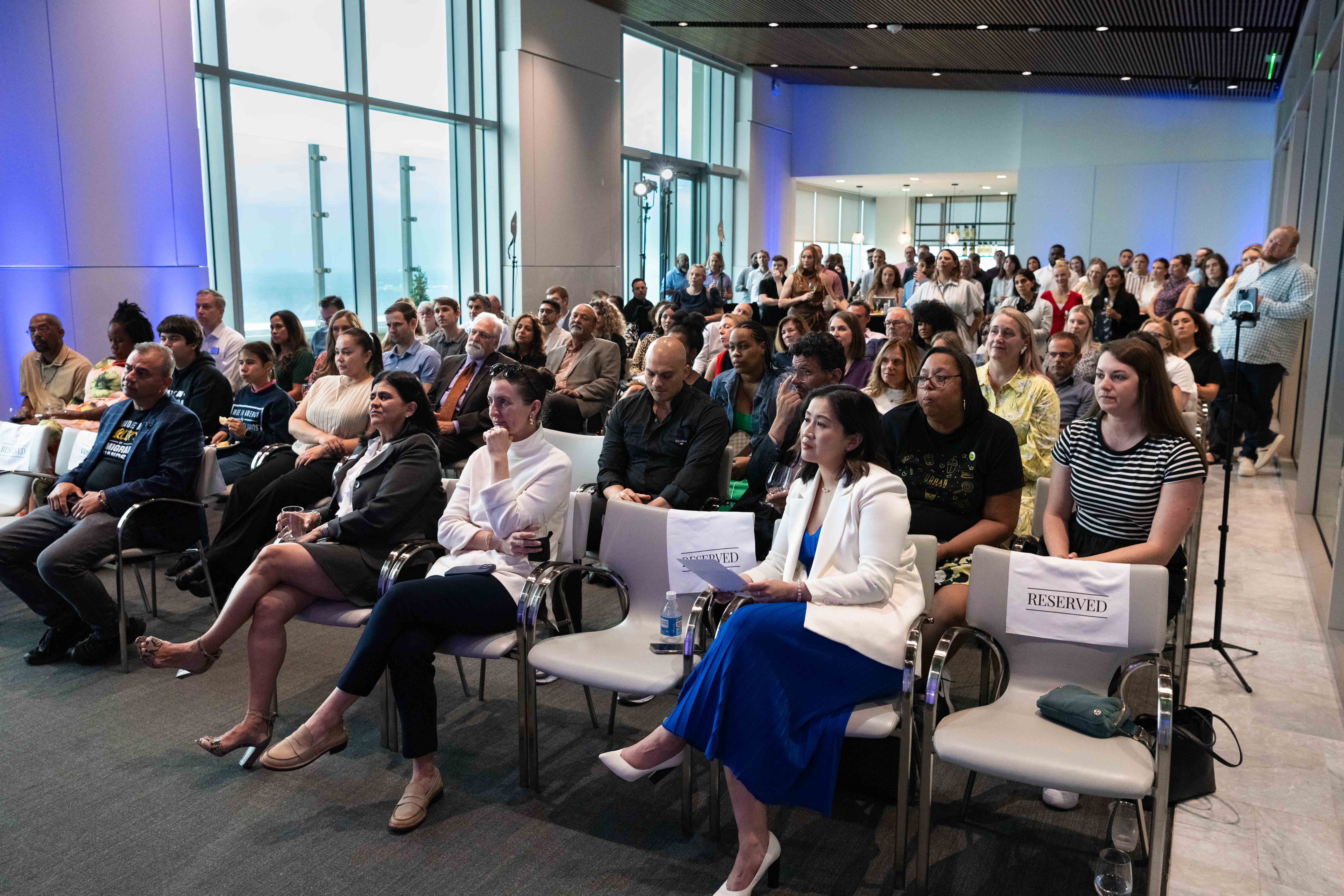 The crowd sits and listens to the speakers onstage. 