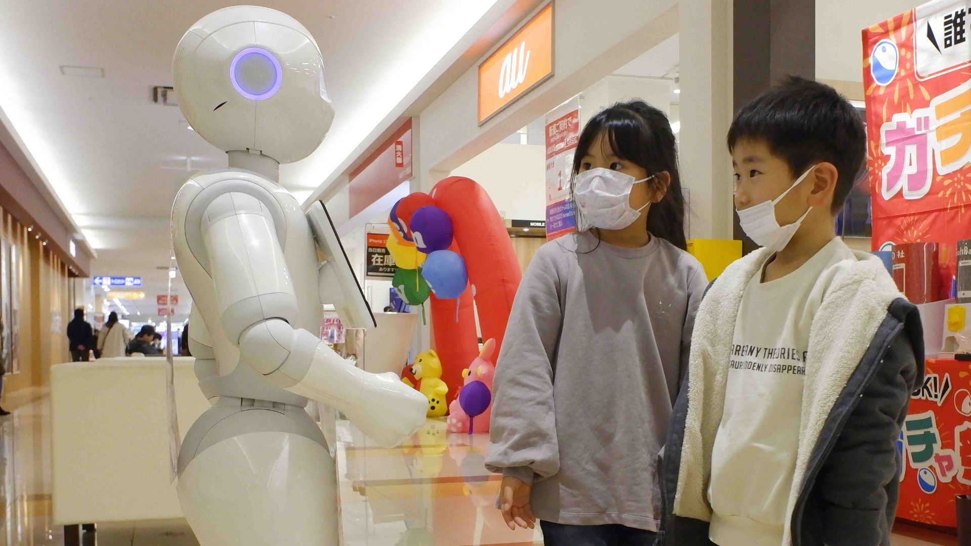 Children in a shopping mall with a life-sized robot.