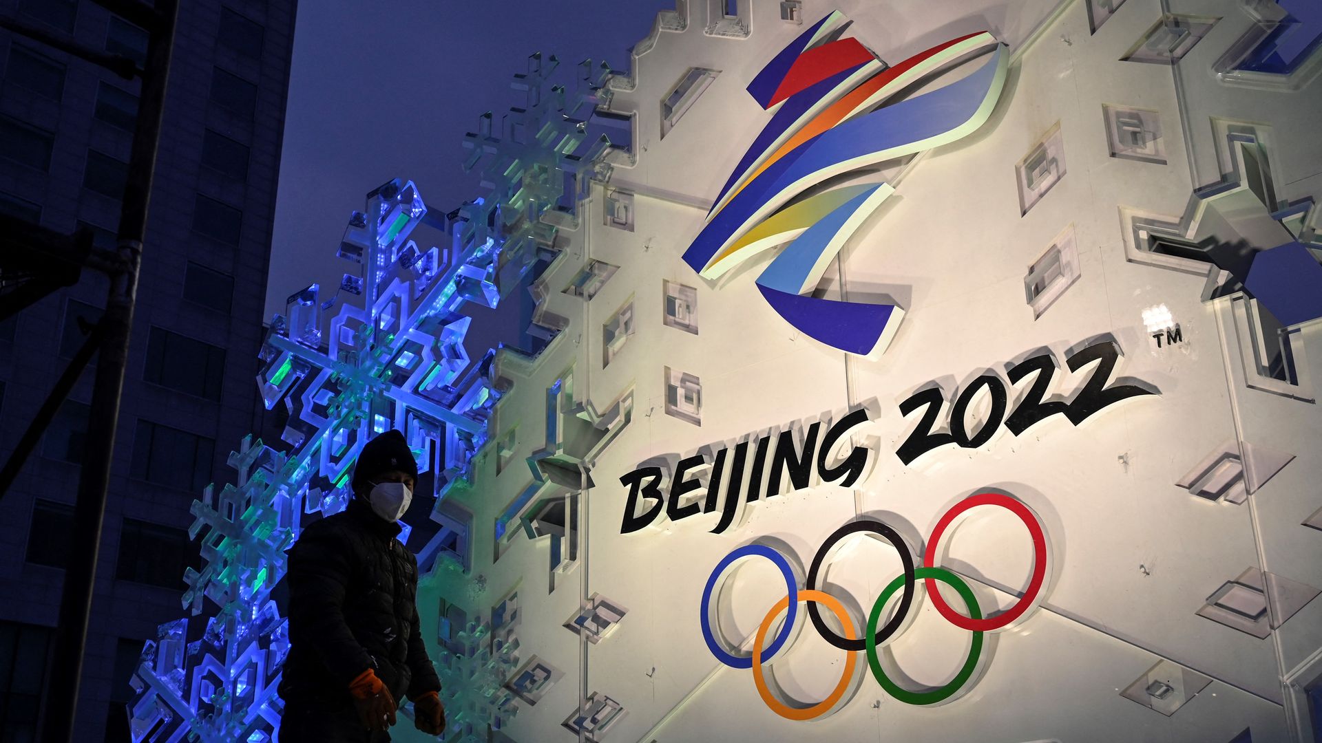 A worker sets up an installation displaying the logo of the Beijing 2022 Winter Olympic Games along a street in Beijing on January 21, 2022.