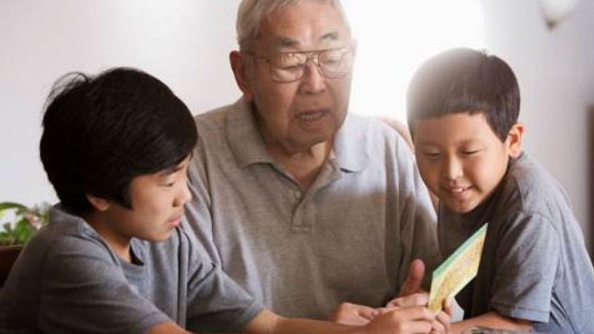 two asian kids reading to an older asian man