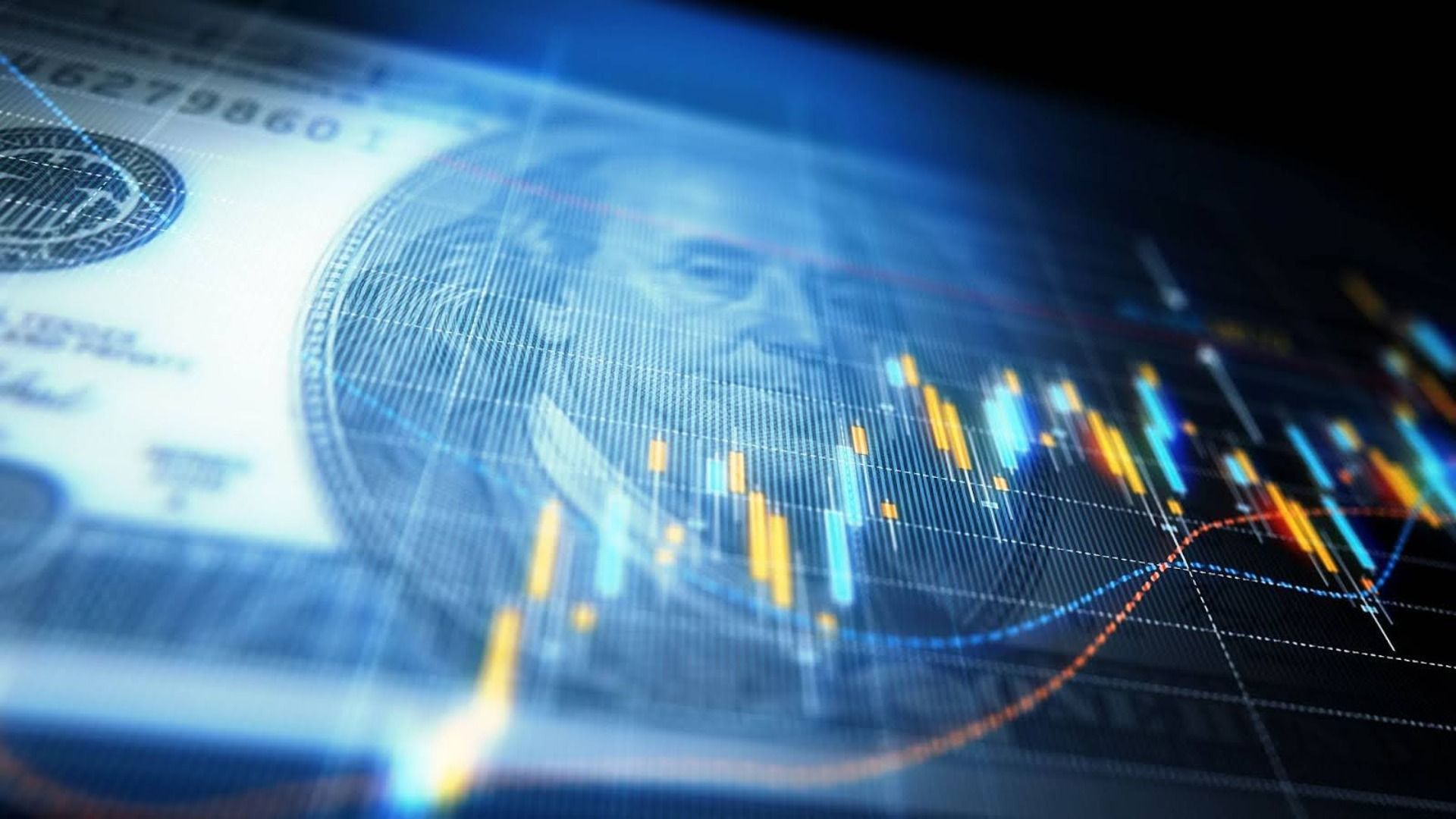 Close-up of a US dollar bill with a translucent overlay of colorful stock market candlestick and line charts in blue, yellow and orange on a dark background.