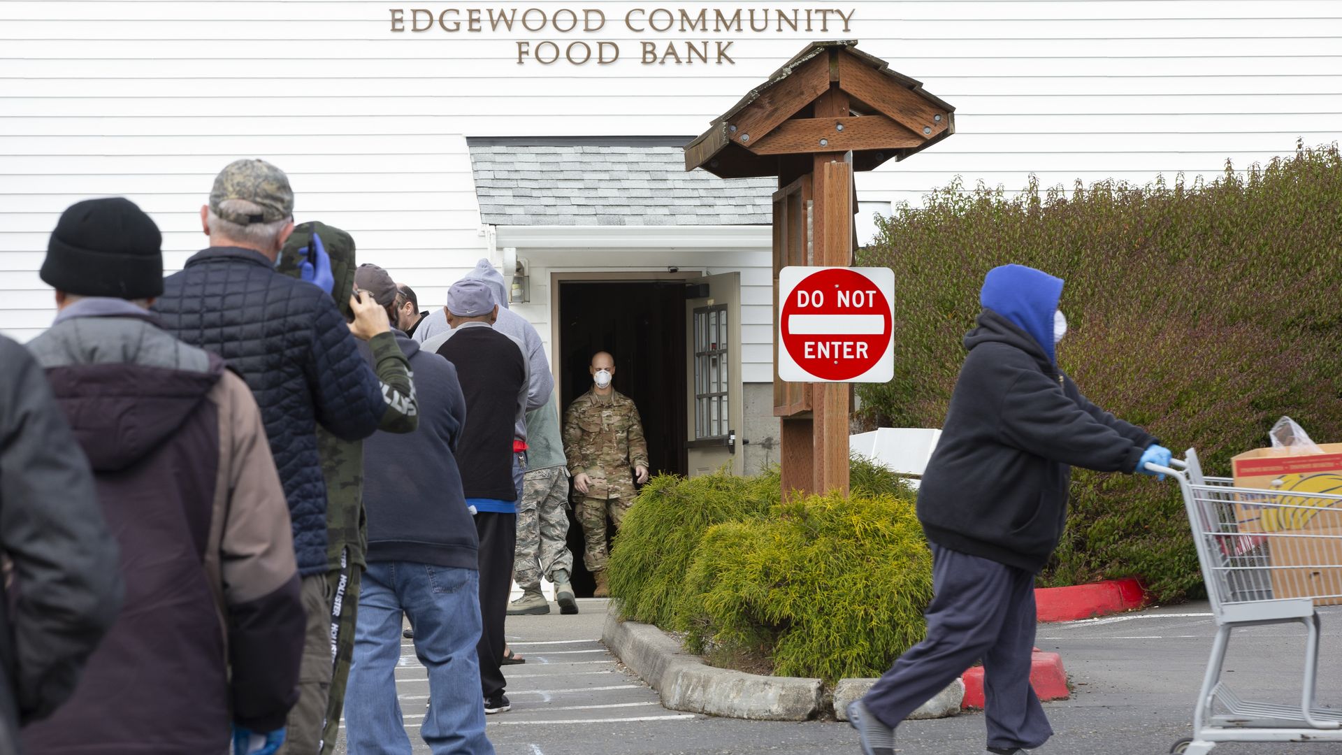 People wait on line standing in squares six-feet apart at the Nourish Pierce County food bank