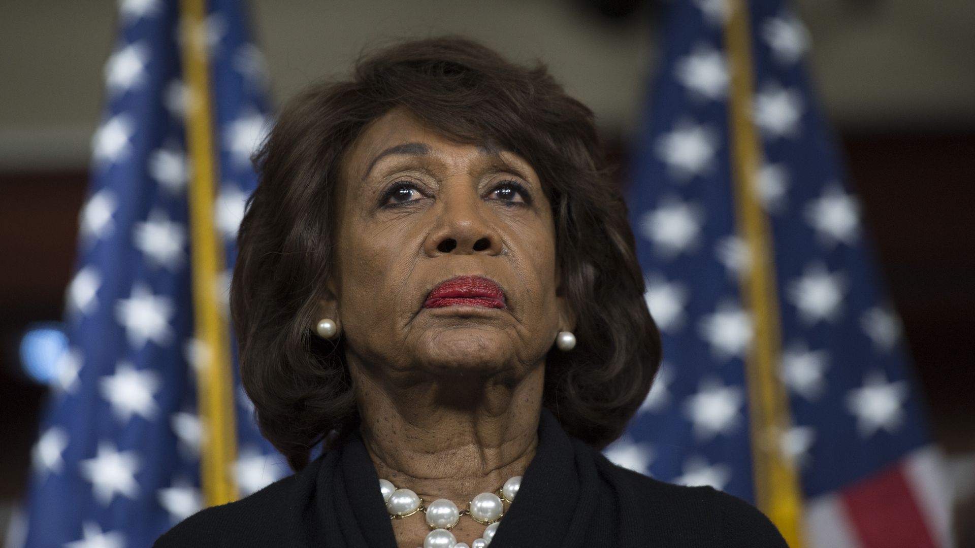 Maxine Waters in a black outfit frowning. 