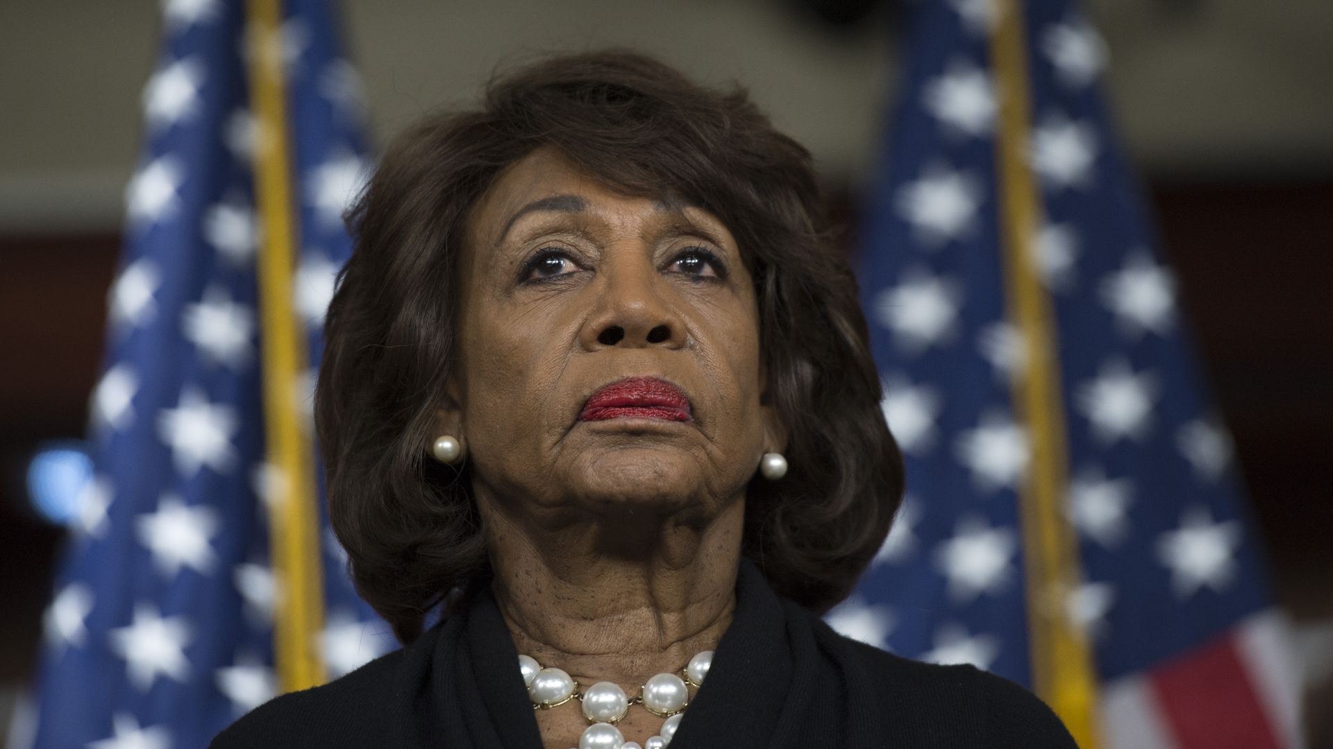 Maxine Waters in a black outfit frowning.