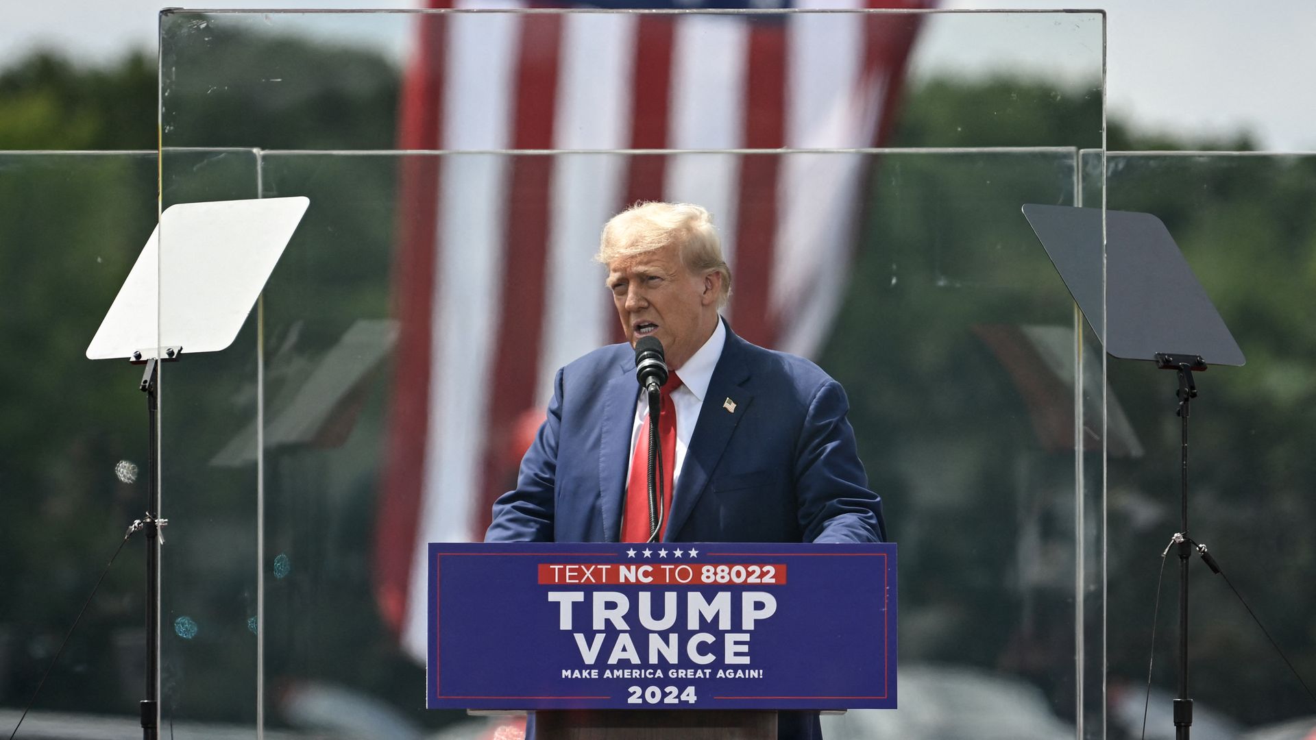 Former US President and Republican presidential candidate Donald Trump speaks behind bulletproof glass during a campaign rally at the North Carolina Aviation Museum & Hall of Fame in Asheboro, North Carolina, August 21.