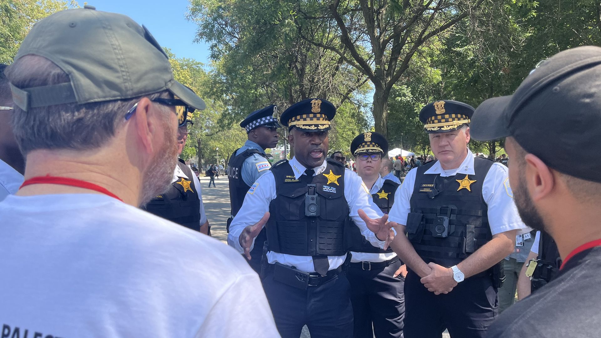 Chicago police officer has hands raised as he talks to two people in baseball caps.