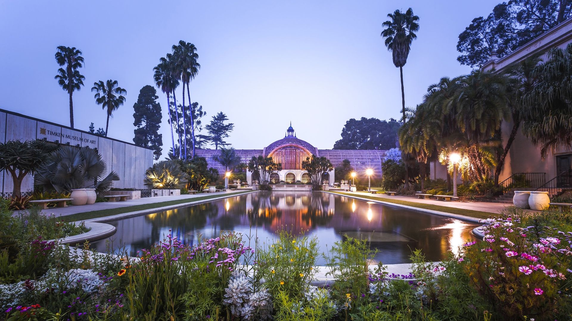 Flowers surround a pond in front of the botanical building at Balboa Park at dusk.