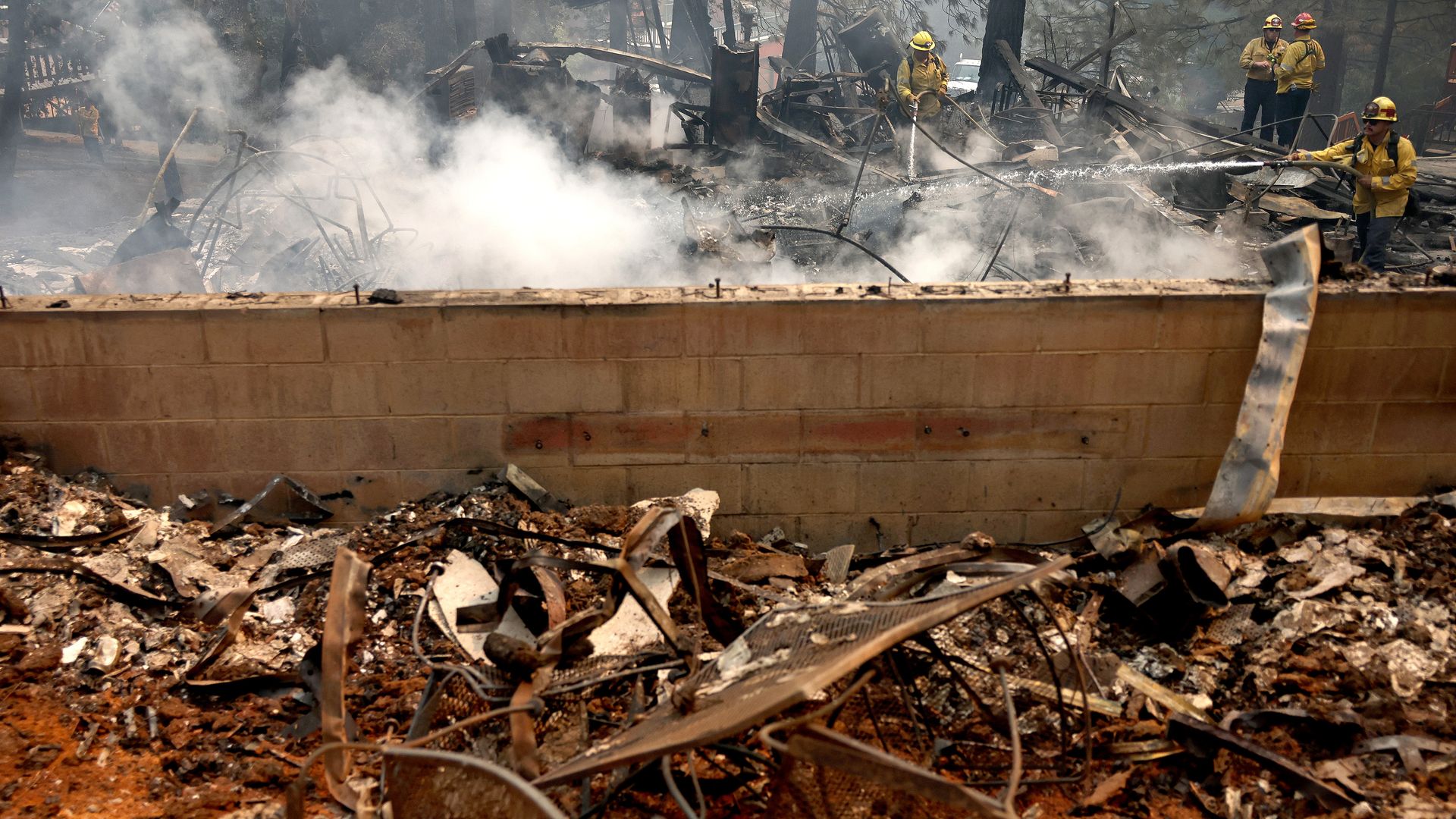 Firefighters spray down the remnants of a destroyed home during the Bridge Fire which has now burned more than 47,000 acres in Angeles National Forest on September 11, 2024 in Wrightwood, California.