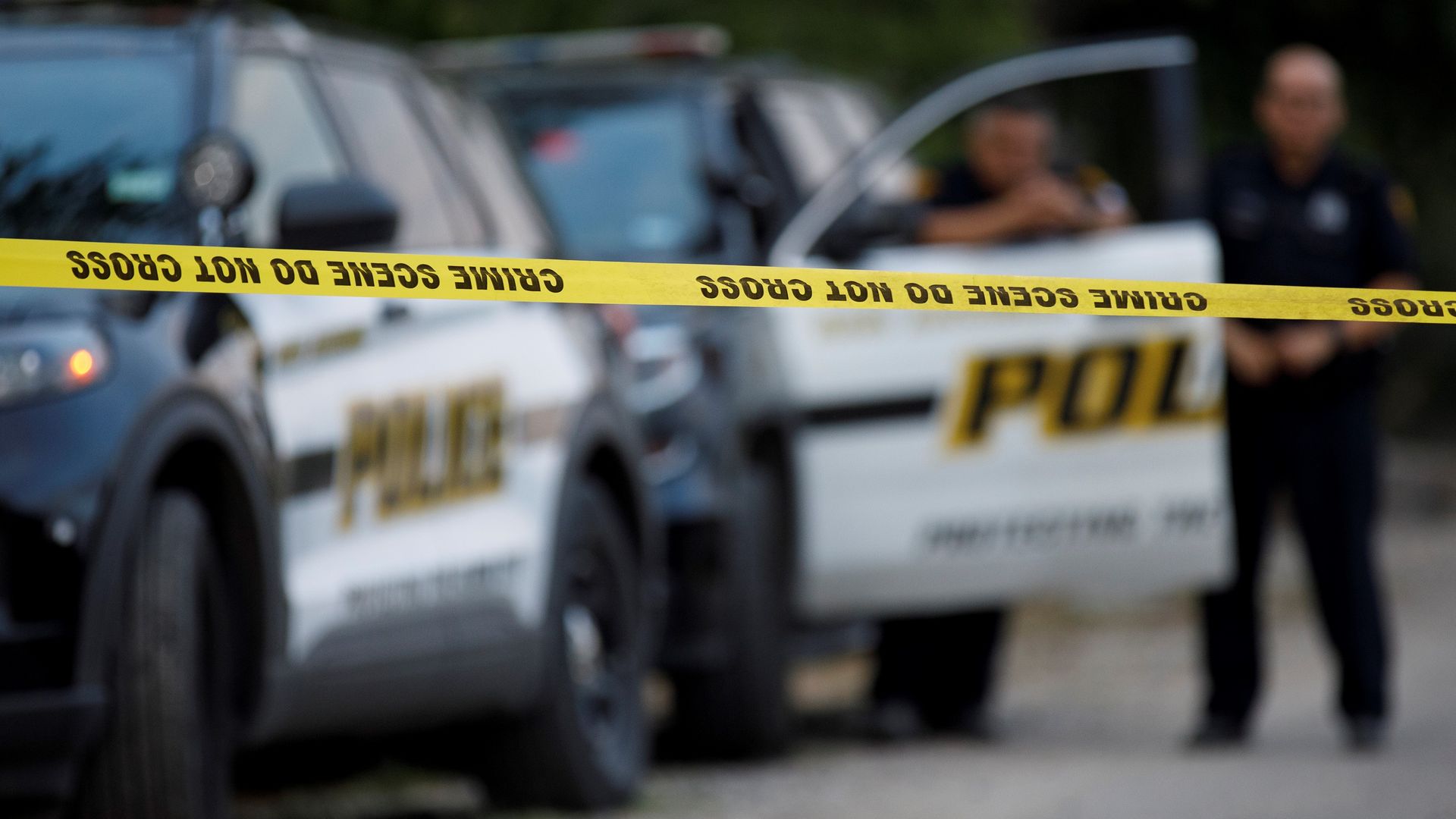 Two San Antonio police cars are seen blurred in the background behind a yellow crime scene tape in this 2022 photo.
