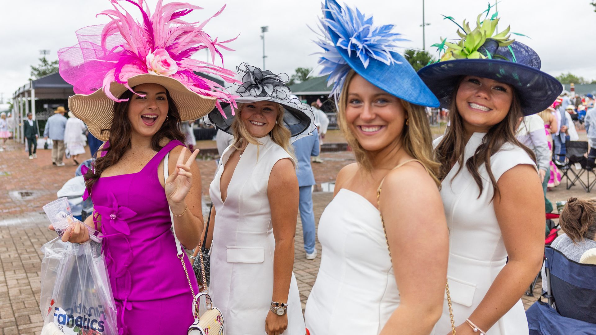 Four women smile wearing hats, one fuchsia, one royal blue, one navy and one black and white.