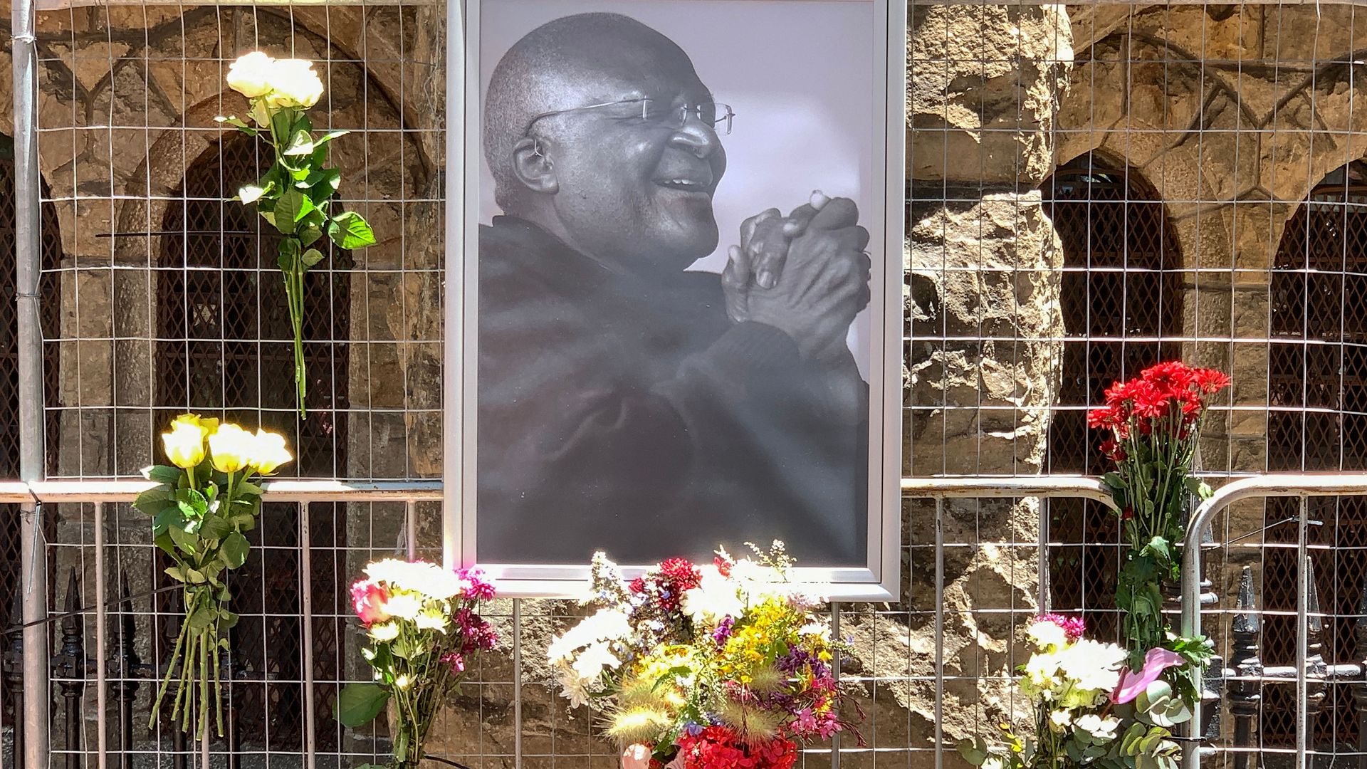 lowers are seen next to a portrait of South African anti-apartheid icon Desmond Tutu outside St. George's cathedral in Cape Town on December 26, 2021