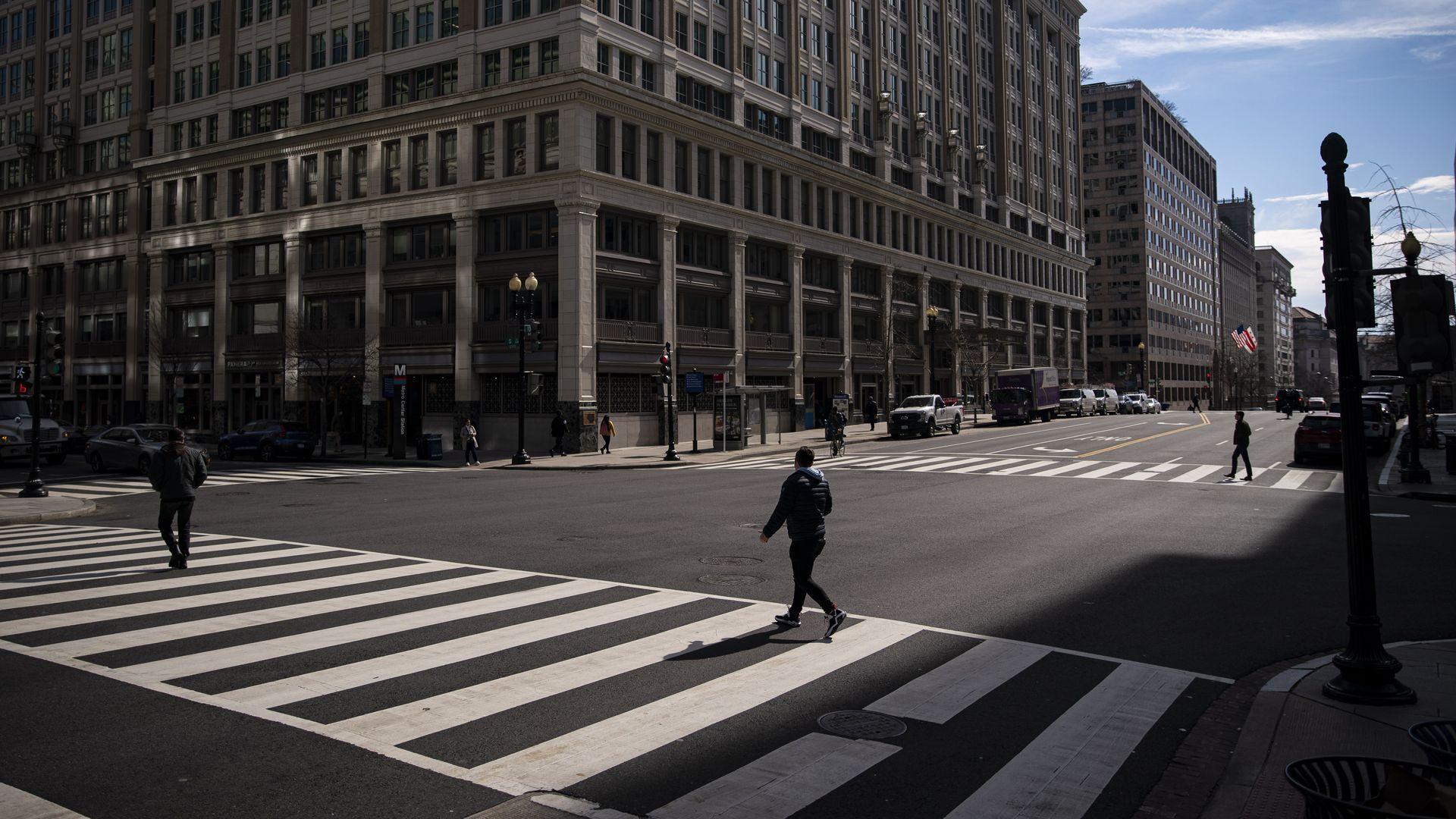 A photo showing pedestrians walking across a crosswalk in front of office buildings.
