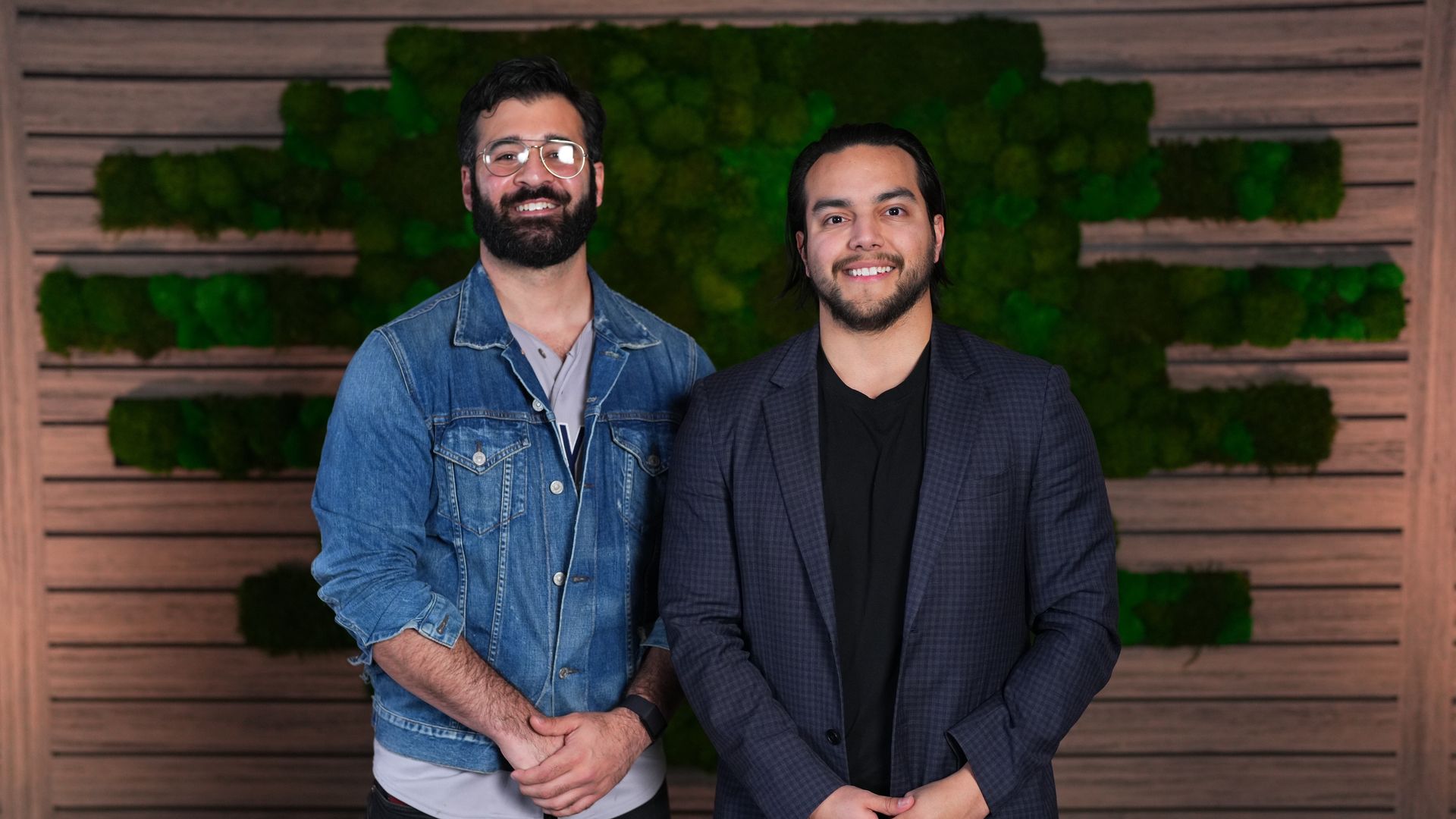 Two men stand side by side with their hands clasped at the front
