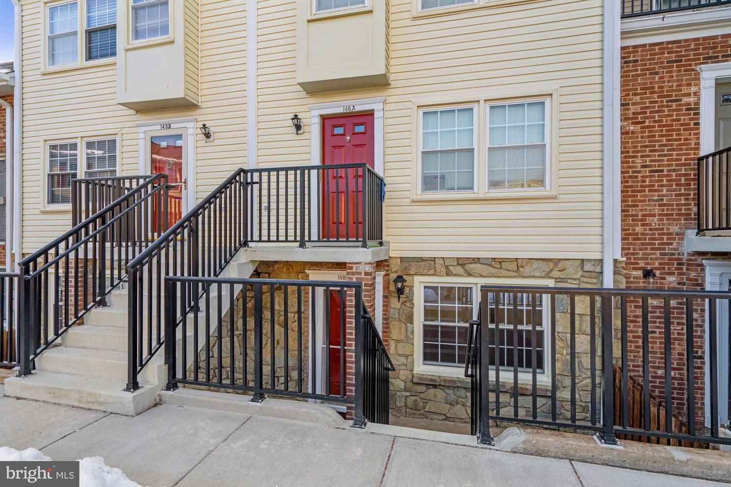 The outside of a condo community with yellow siding and red doors.