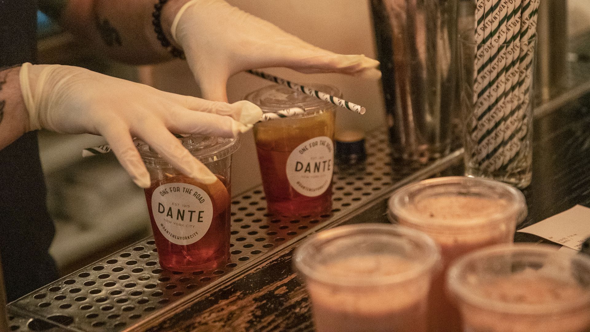 Picture of hands wearing globes about to grab two plastic cups with iced tea