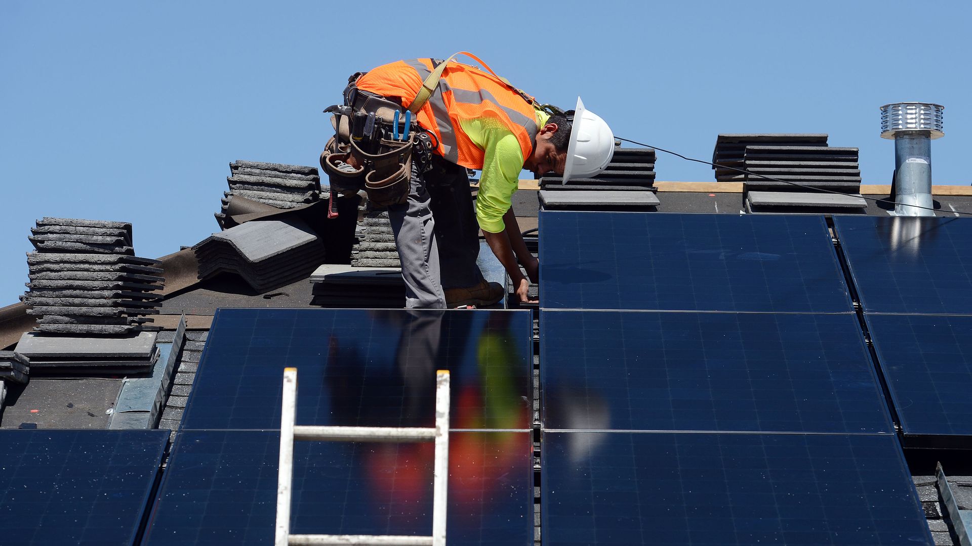 A worker installs solar panels on a roof