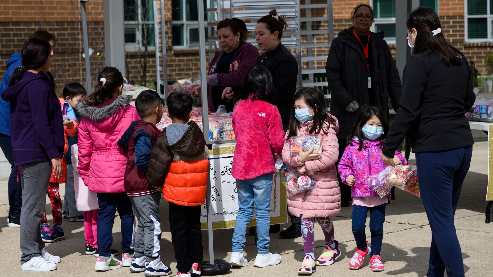 Children, some wearing face masks as a preventive measure, pick up free lunch
