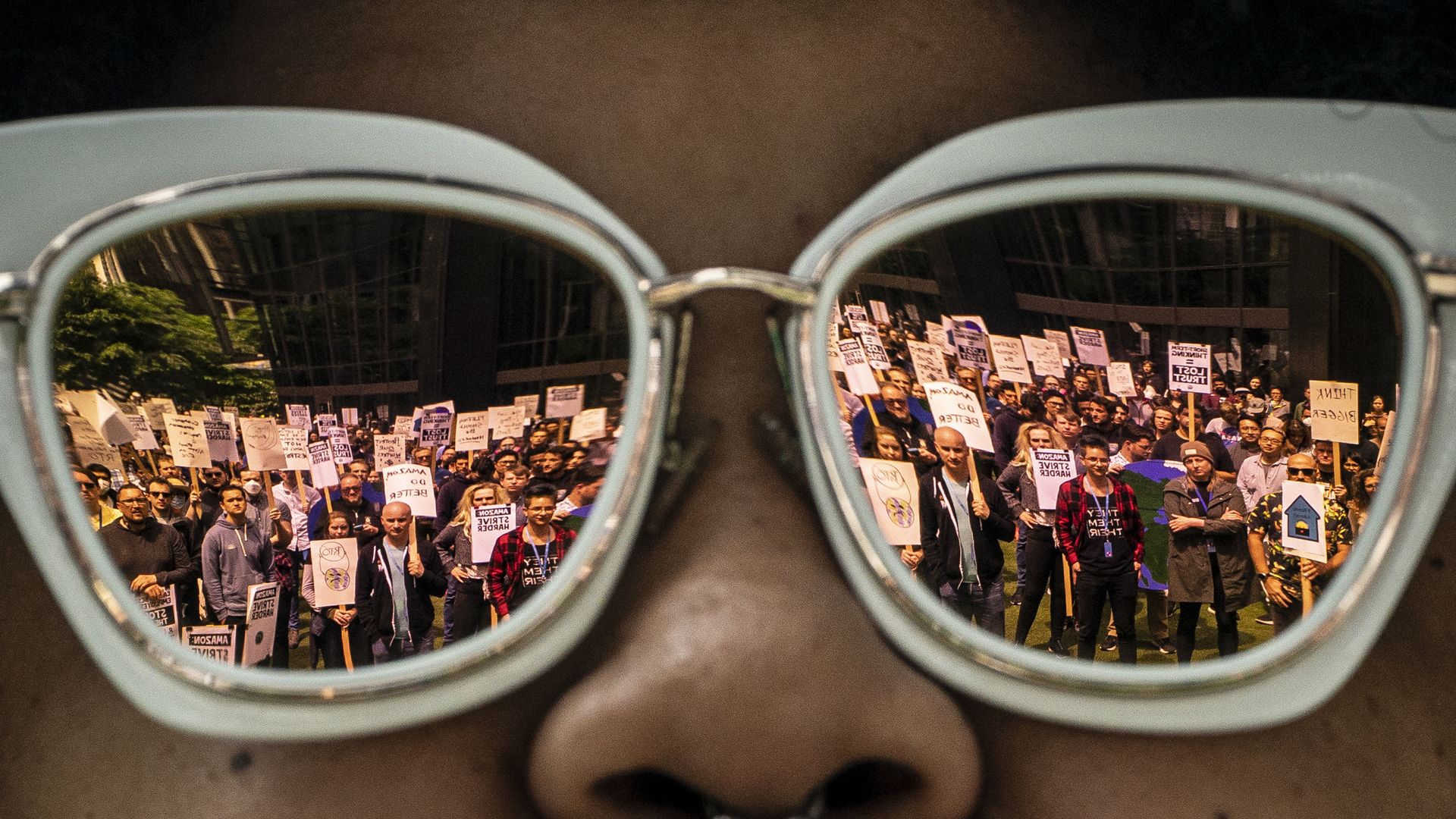 A crowd of protestors are reflected in a pair of sunglasses. 