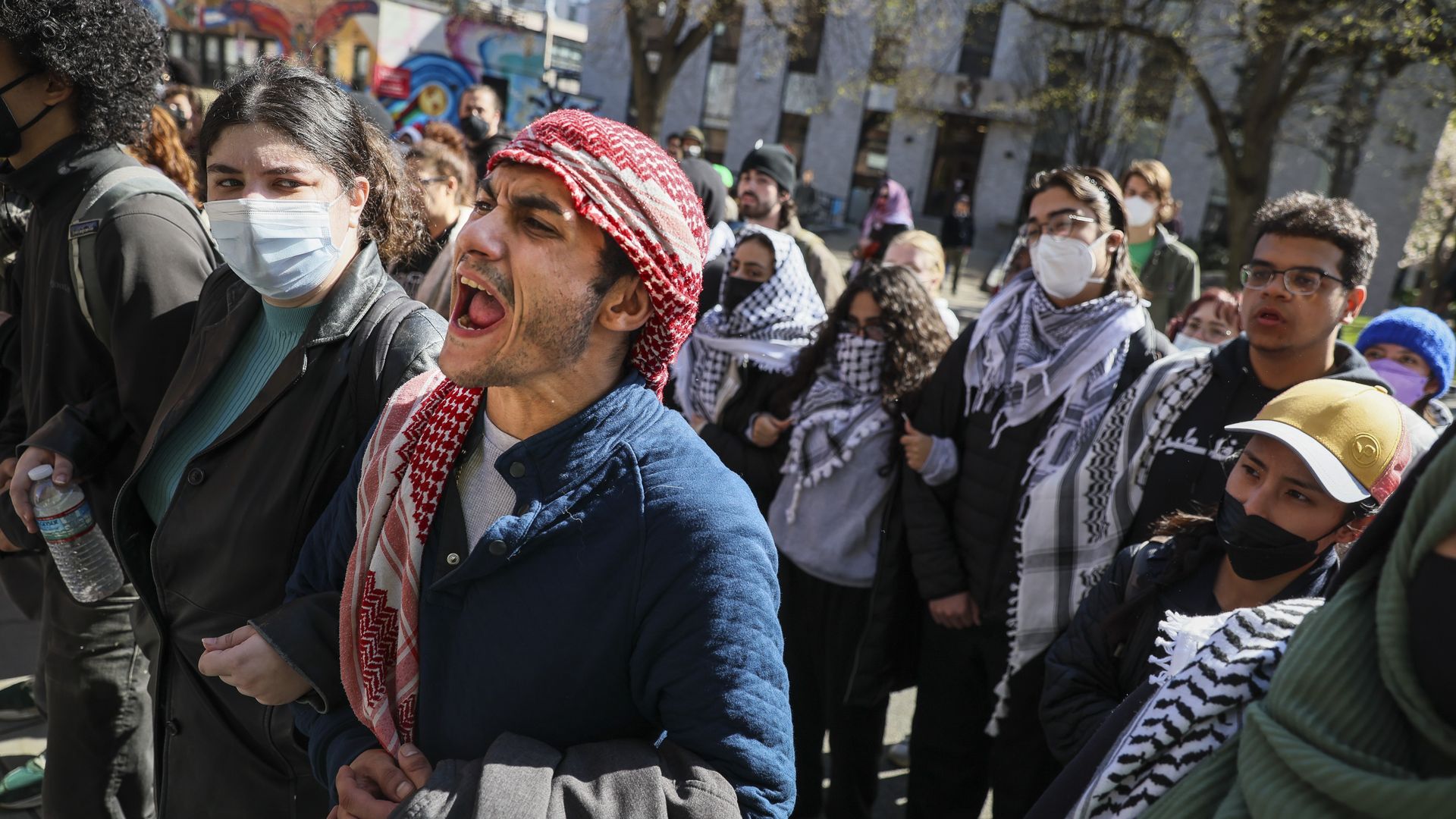 Protesters at Northeastern University shout chants as they support fellow demonstrators as they are placed into nearby police vans early Saturday morning. 