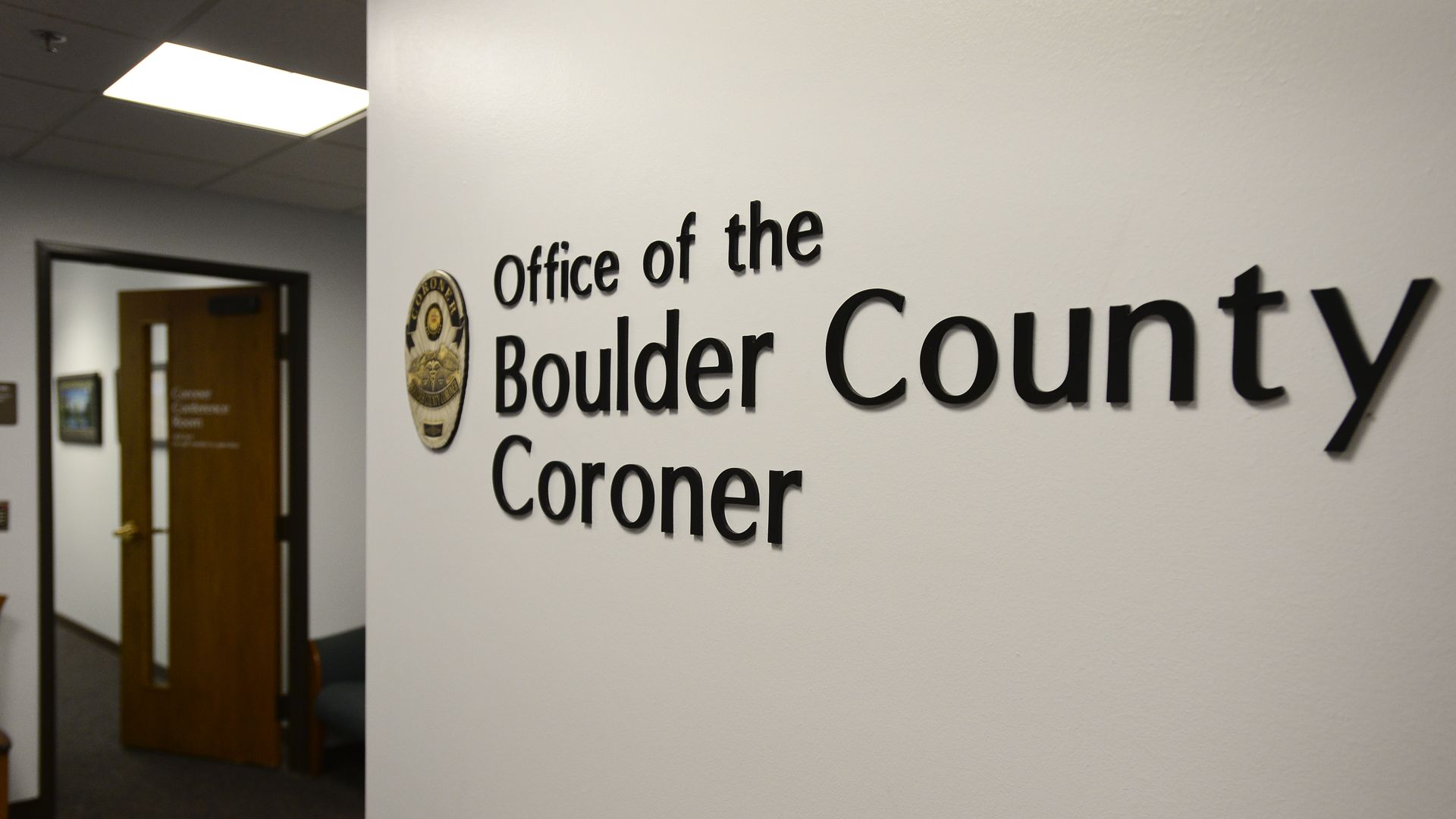 A sign for the Boulder County Coroner's Office is seen on a wall.