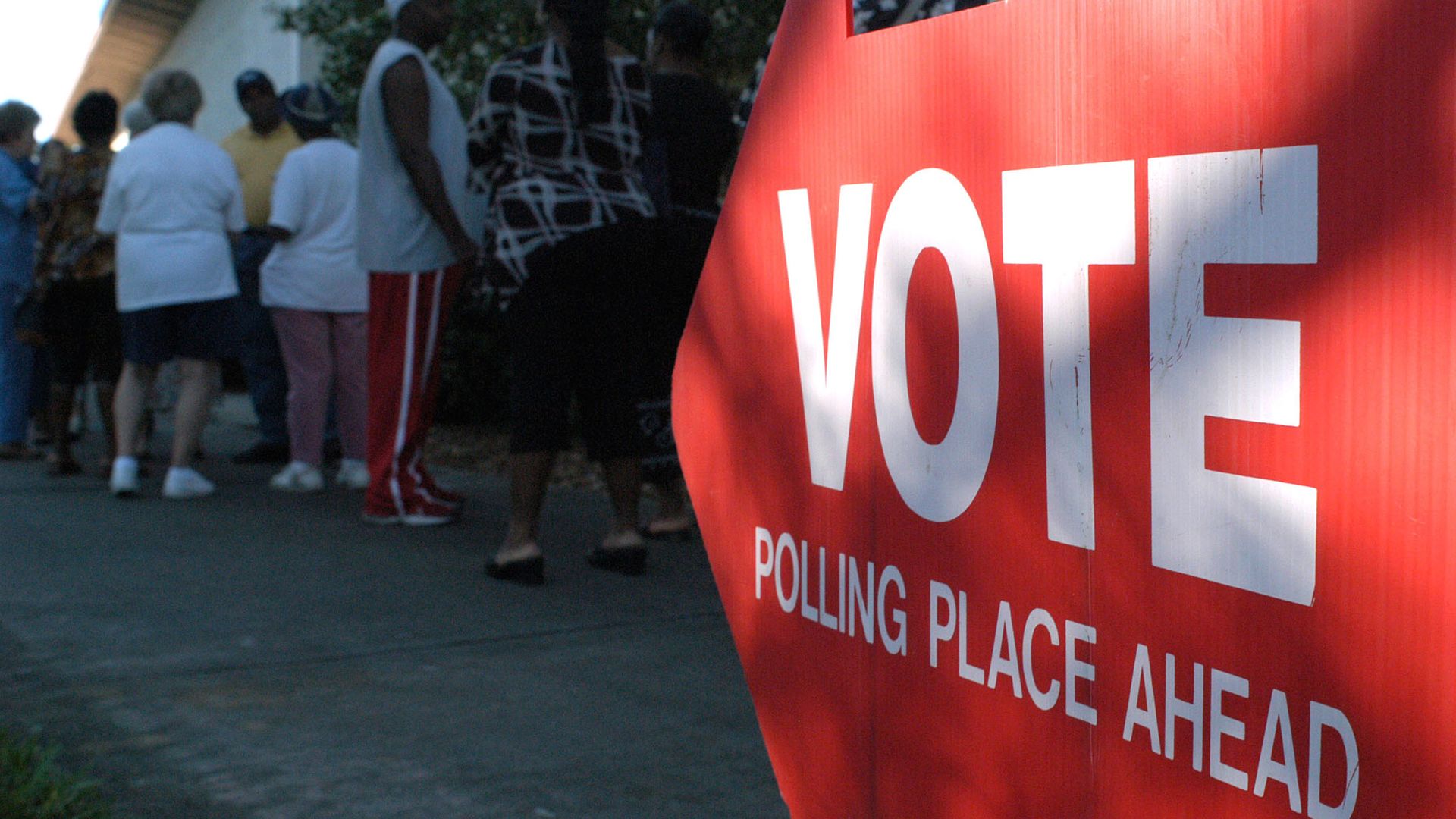A red arrow sign pointing left with the words "vote polling place ahead" in white lettering 