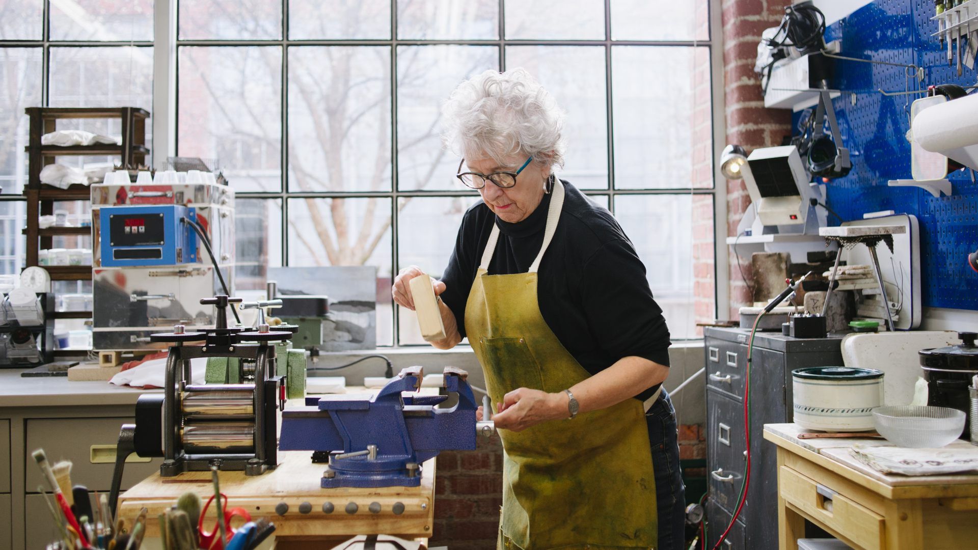 An elderly woman doing some wood working. 