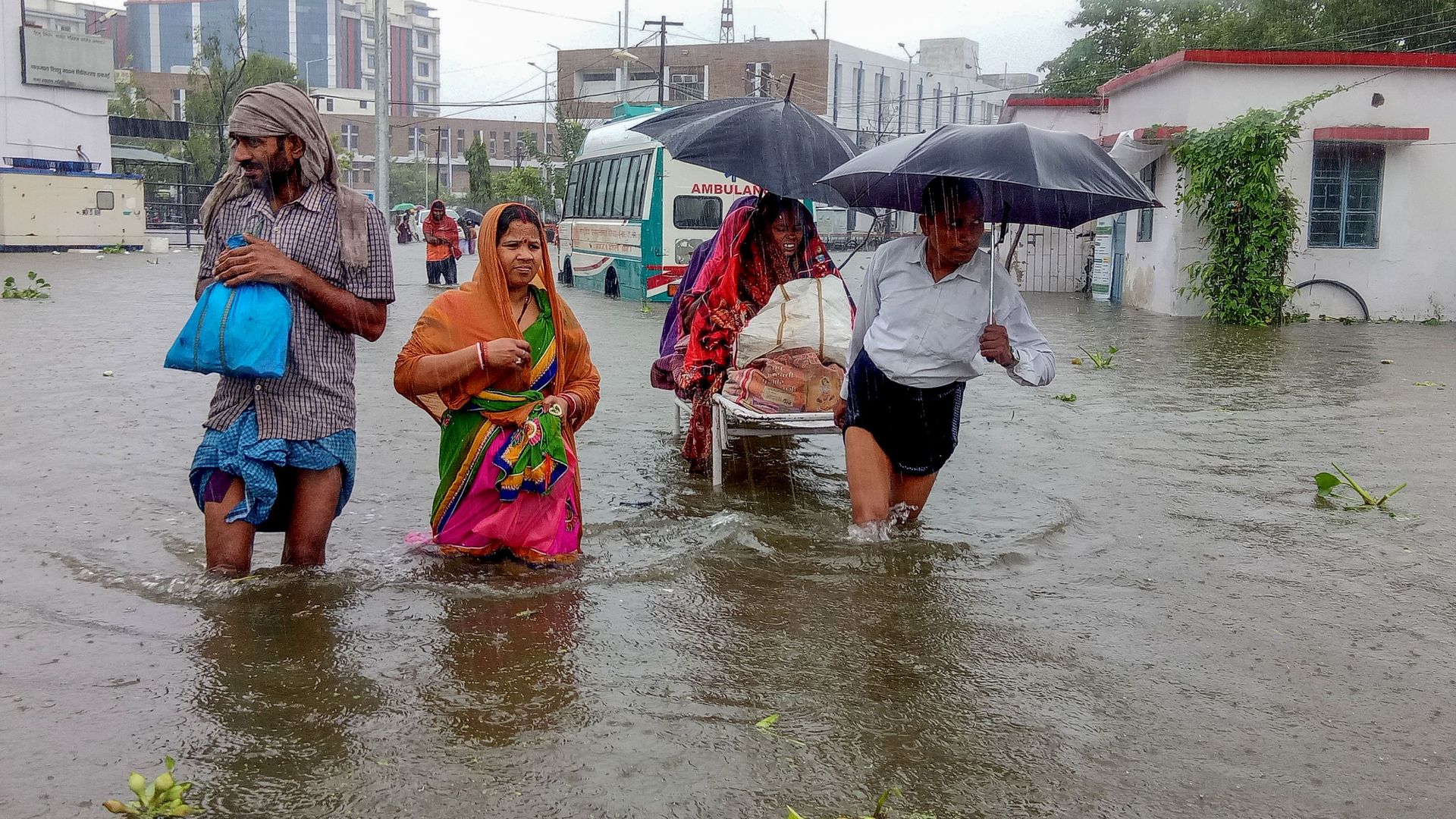 Patients wade through floodwaters on their way to hospital during heavy monsoon rain in Patna in the northeastern state of Bihar on September 28