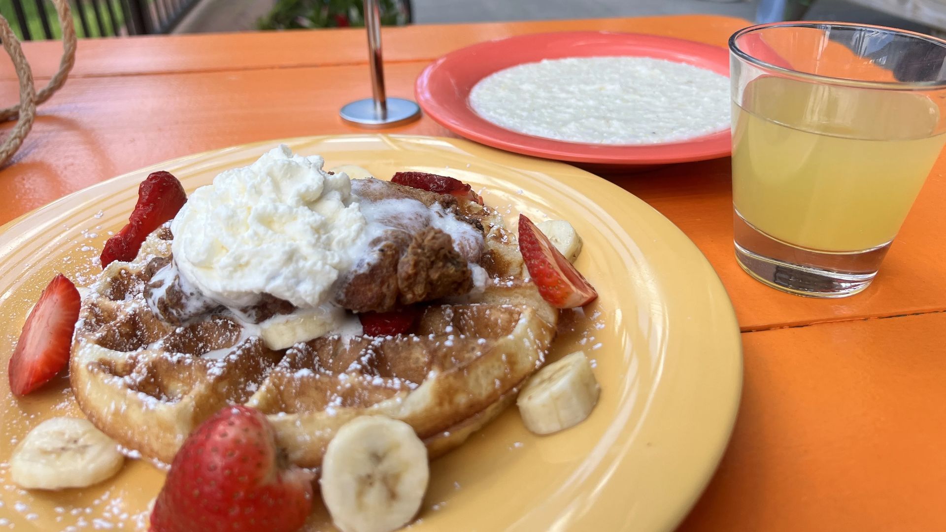 The B-Y-O waffle, with fried chicken, bananas, strawberries and whipped cream with a side of grits and a mimosa. Photo: Laura Barrero/Axios