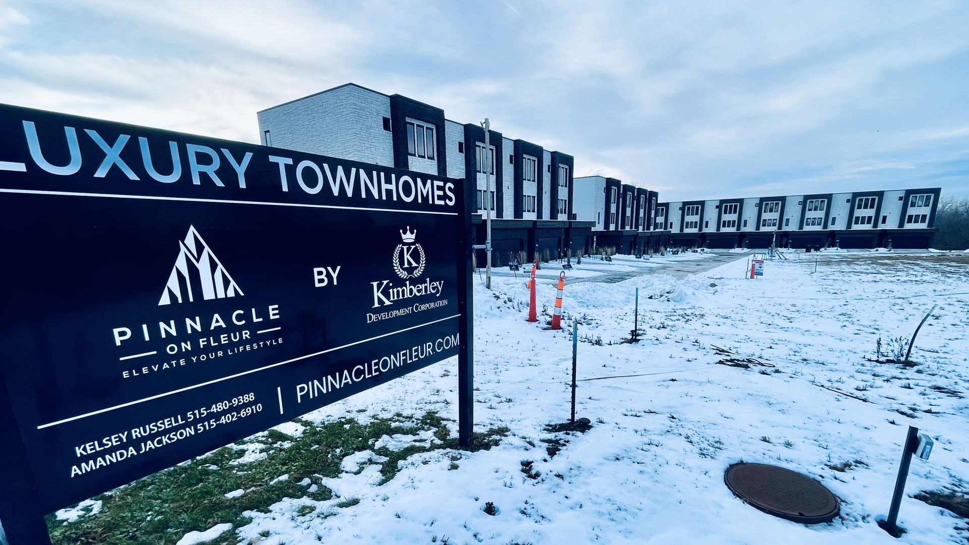 Snow-covered construction site with new modern white and black luxury townhomes and a black sign for Pinnacle on Fleur by Kimberley Development.