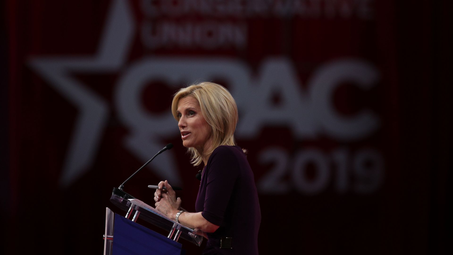 In this image, Laura stands behind a podium on stage.