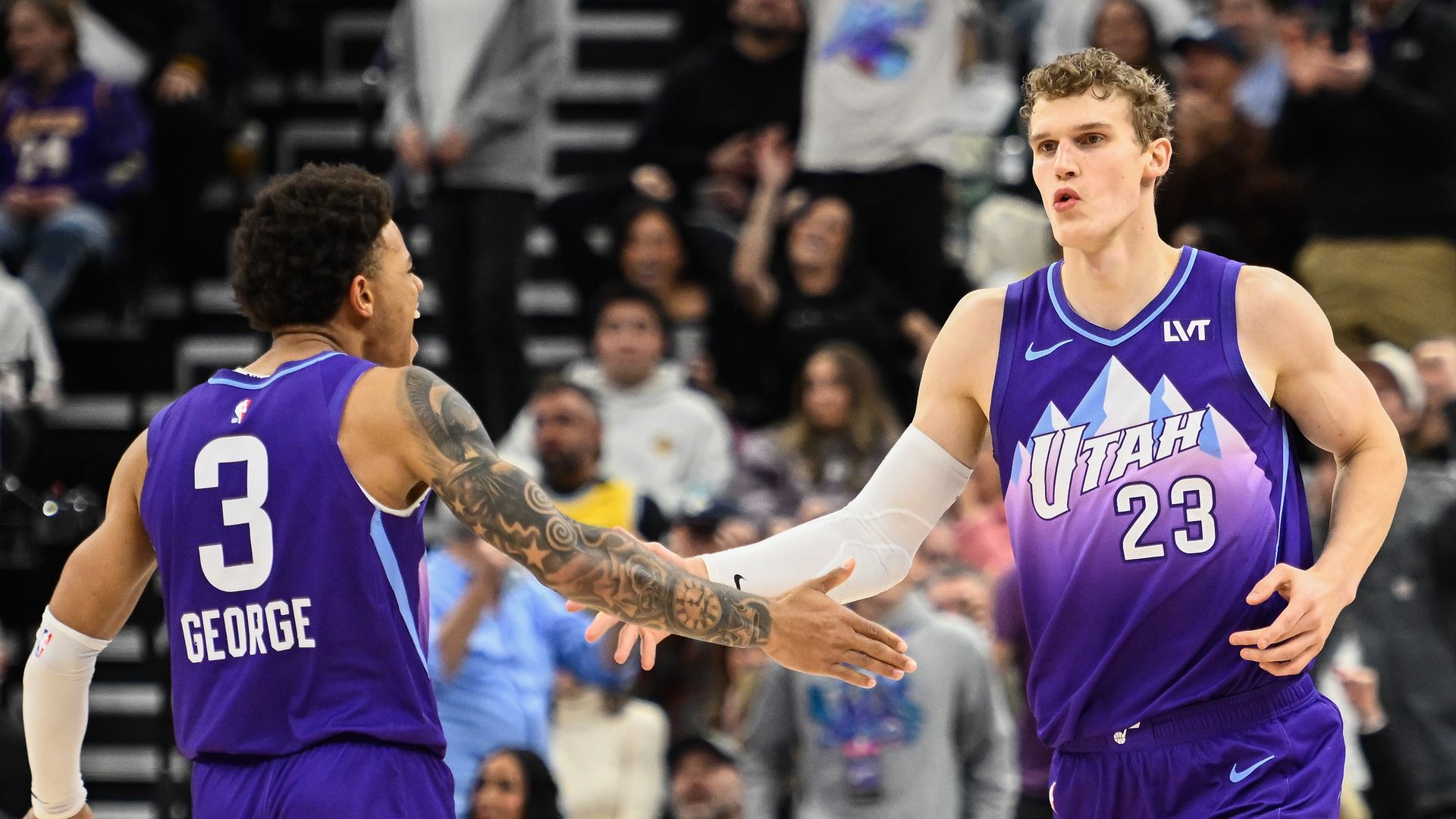 Two men in a purple basketball uniform high five