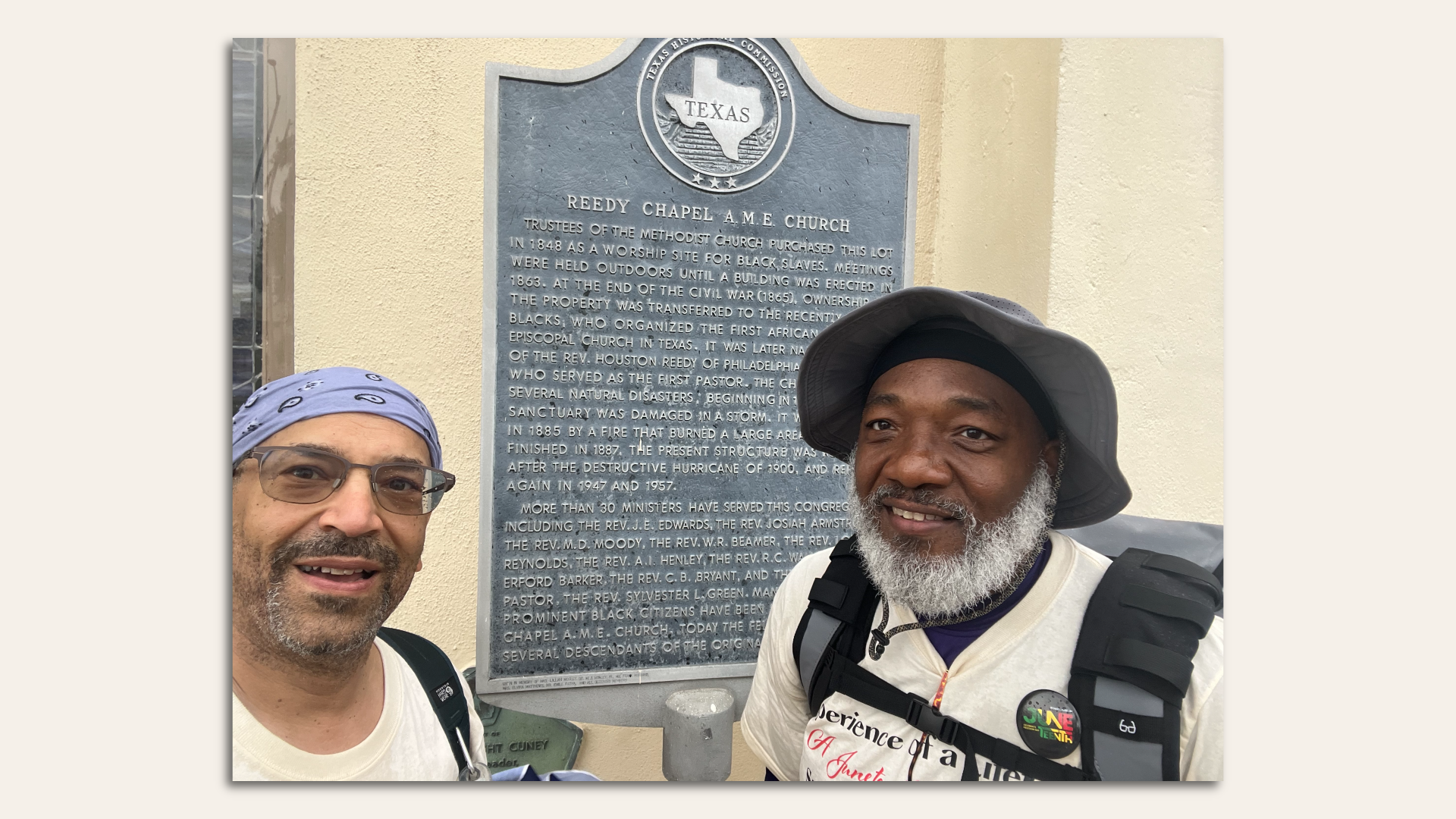two men stand in front of a historical marker