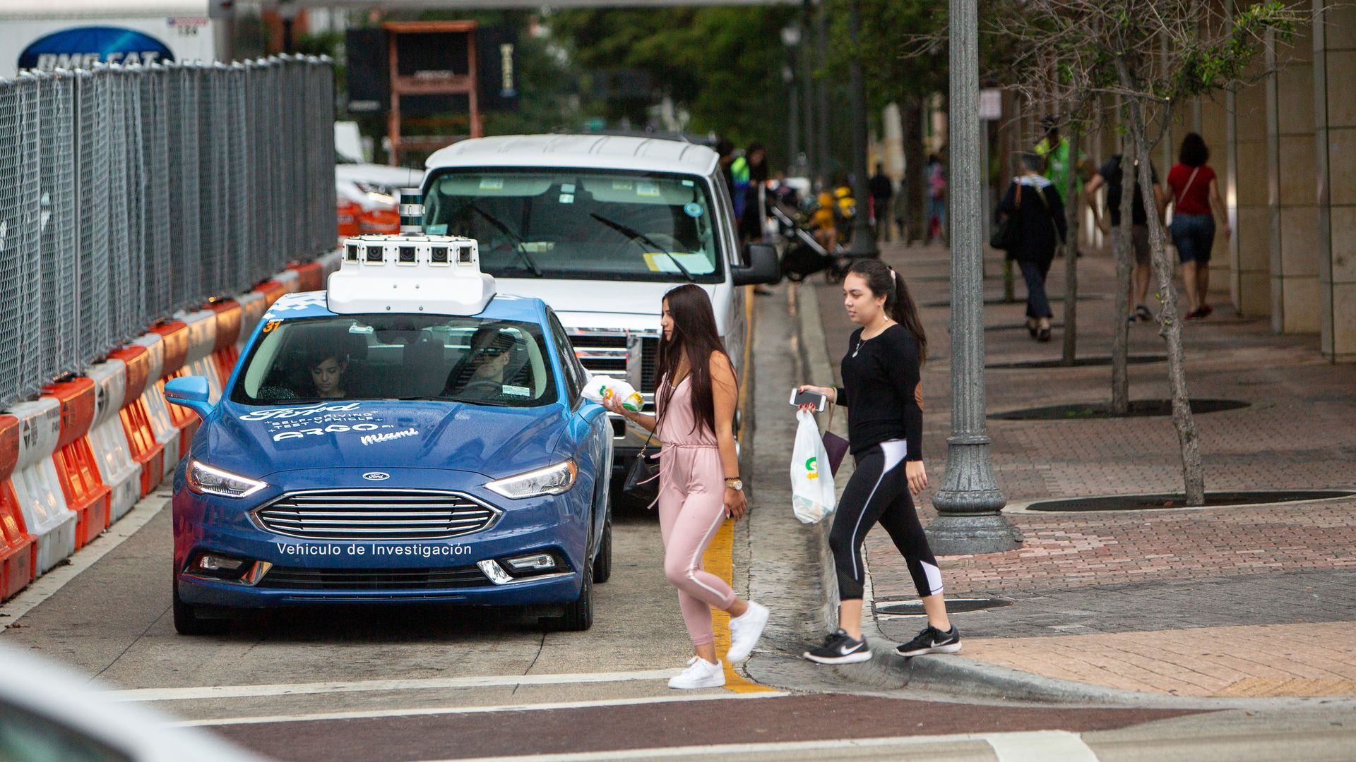 Image of pedestrians crossing in front of an autonomous test vehicle in a Miami construction zone.