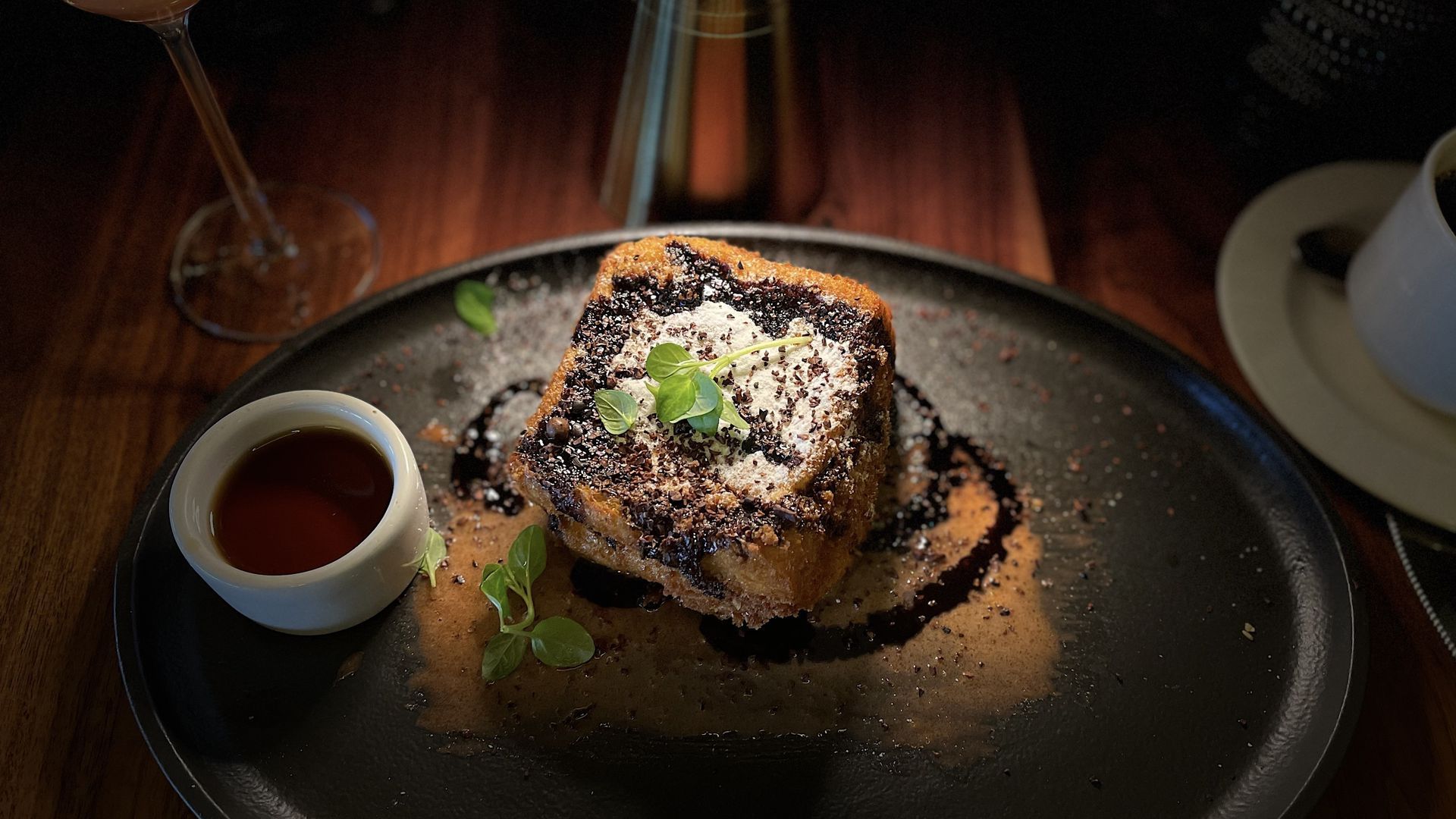 Fried french toast sits on a plate with a side of syrup