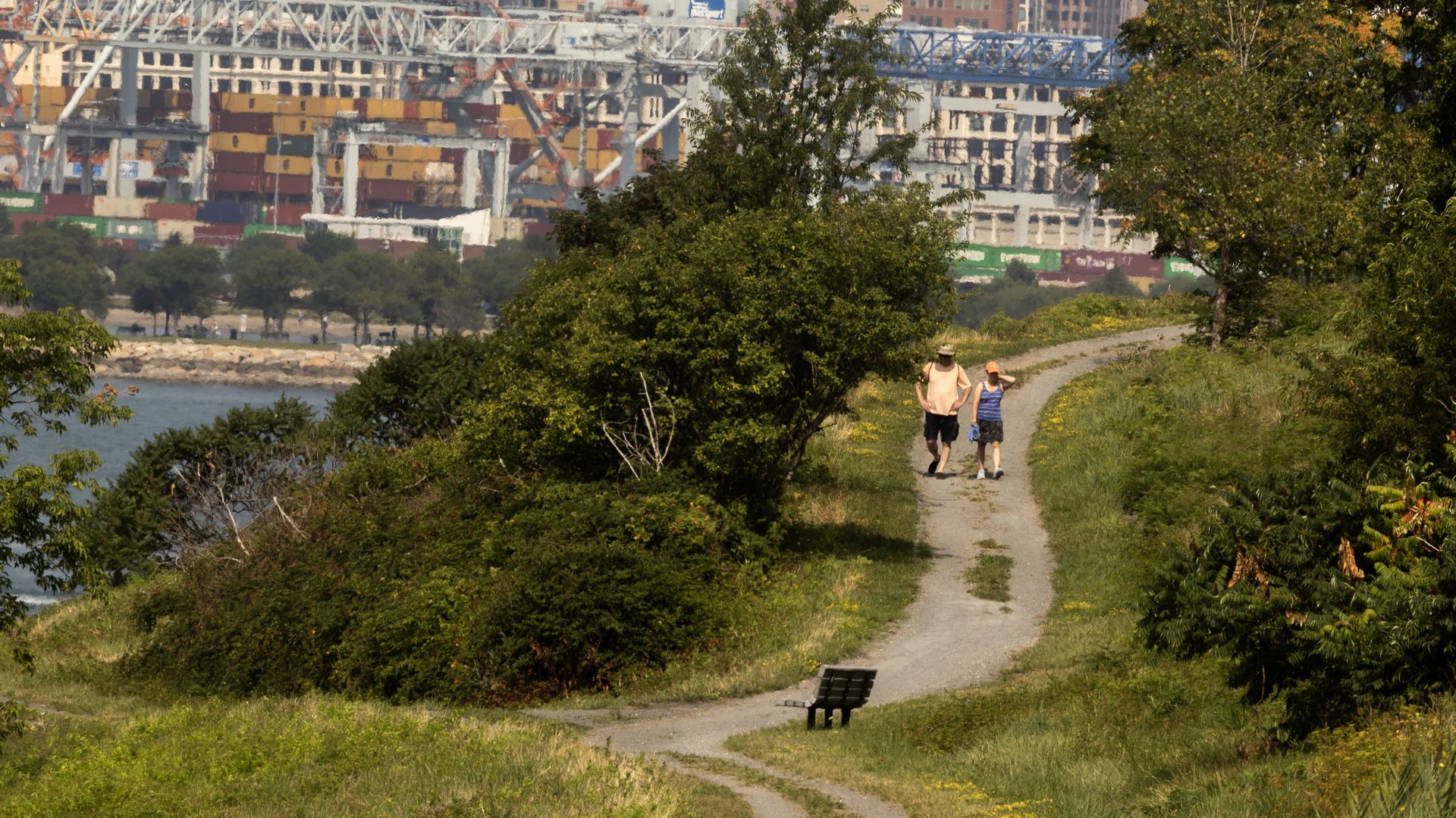 Two people in the distance are seen walking on a trail along the northern drumlin of Spectacle Island in Aug. 2, 2025.