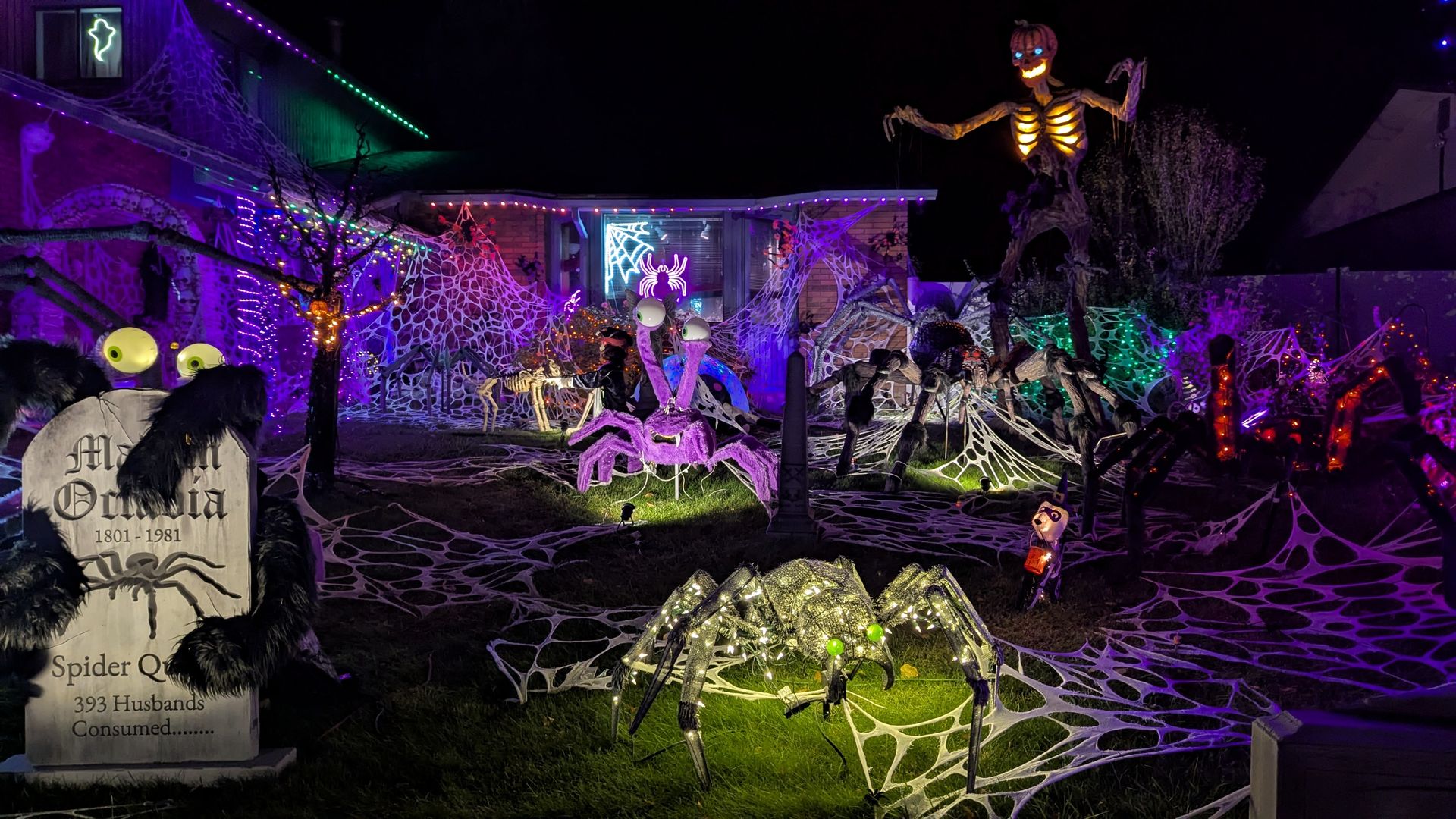 A house covered with decorative spider webs, spiders and other Halloween decorations.