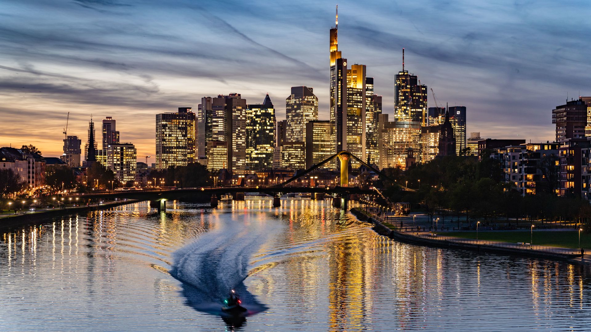 Frankfurt's skyline, filled with skyscrapers and is nearby a waterway. 