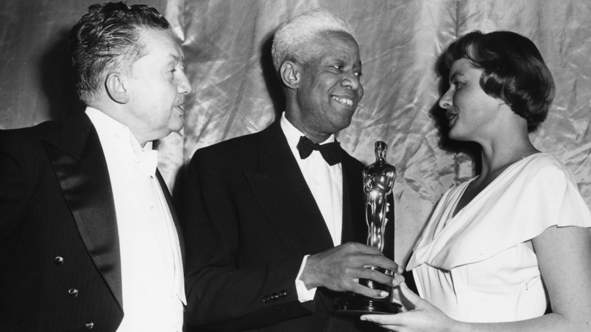 Actor James Baskett (centre) receiving his Honorary Oscar from Ingrid Bergman and Jean Hersholt, at the 20th Academy Awards, Los Angeles, March 20th 1948. 
