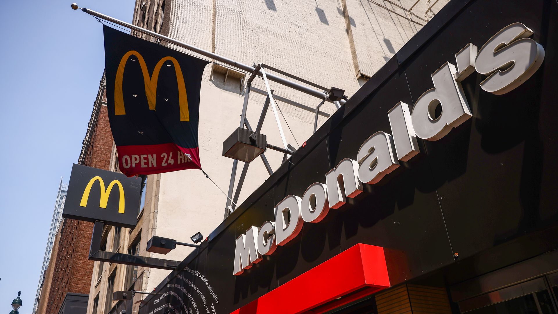A McDonald's restaurant sign with M logo flags flying above. 