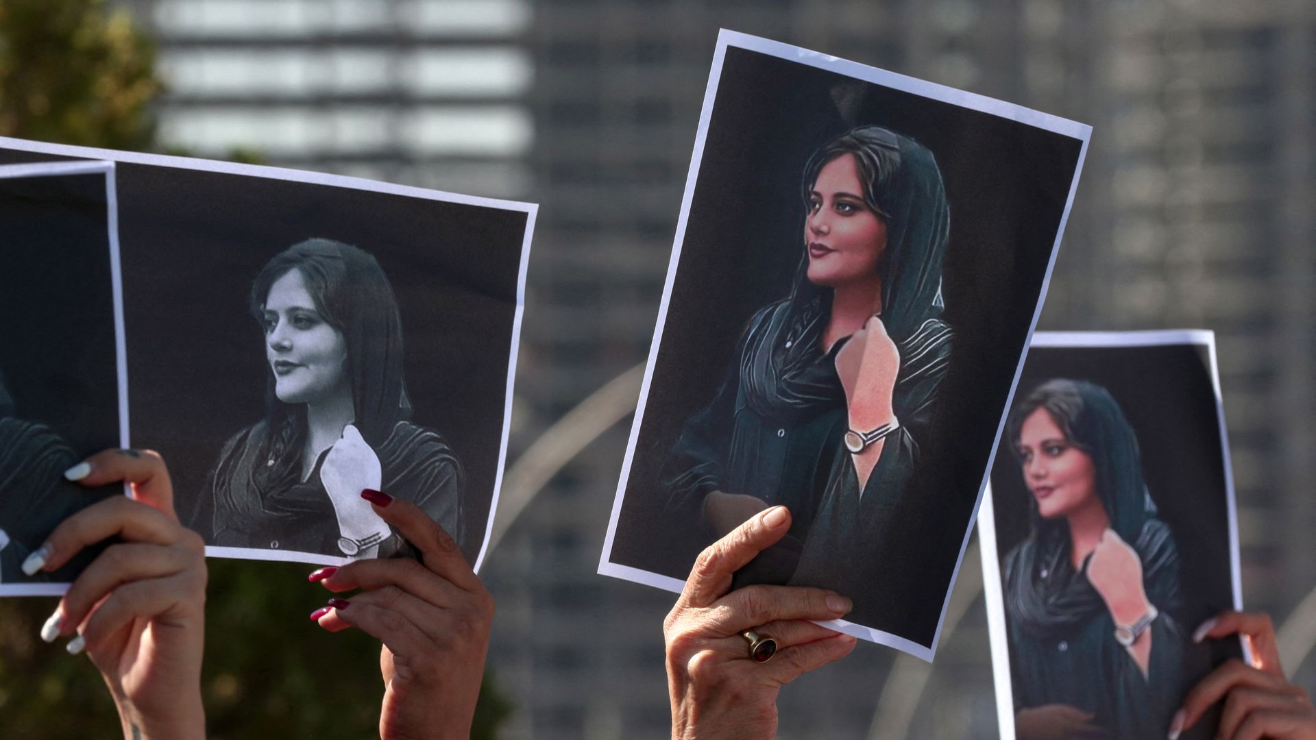 Protesters hold signs of Iranian woman killed by police