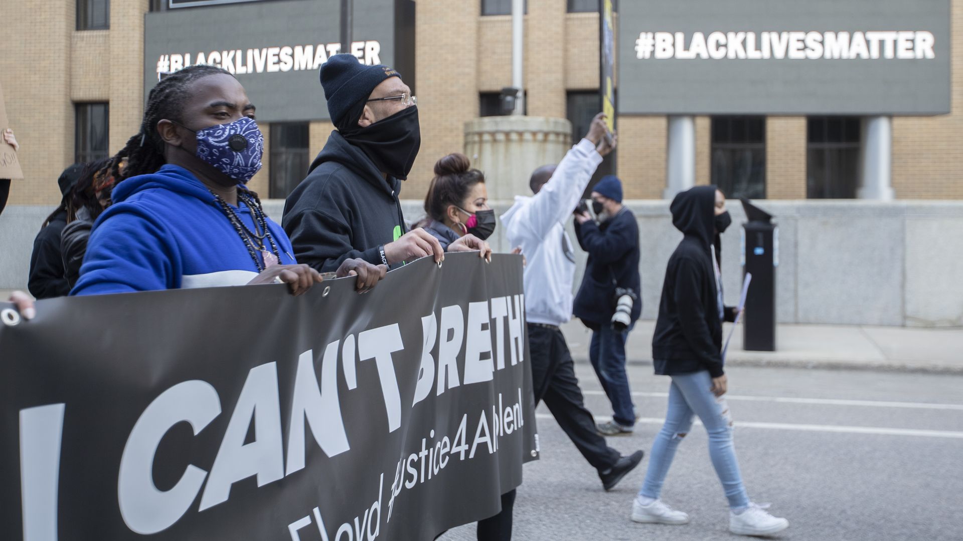 Photo of protesters holding a banner that says "I can't breathe" as they walk on a street 