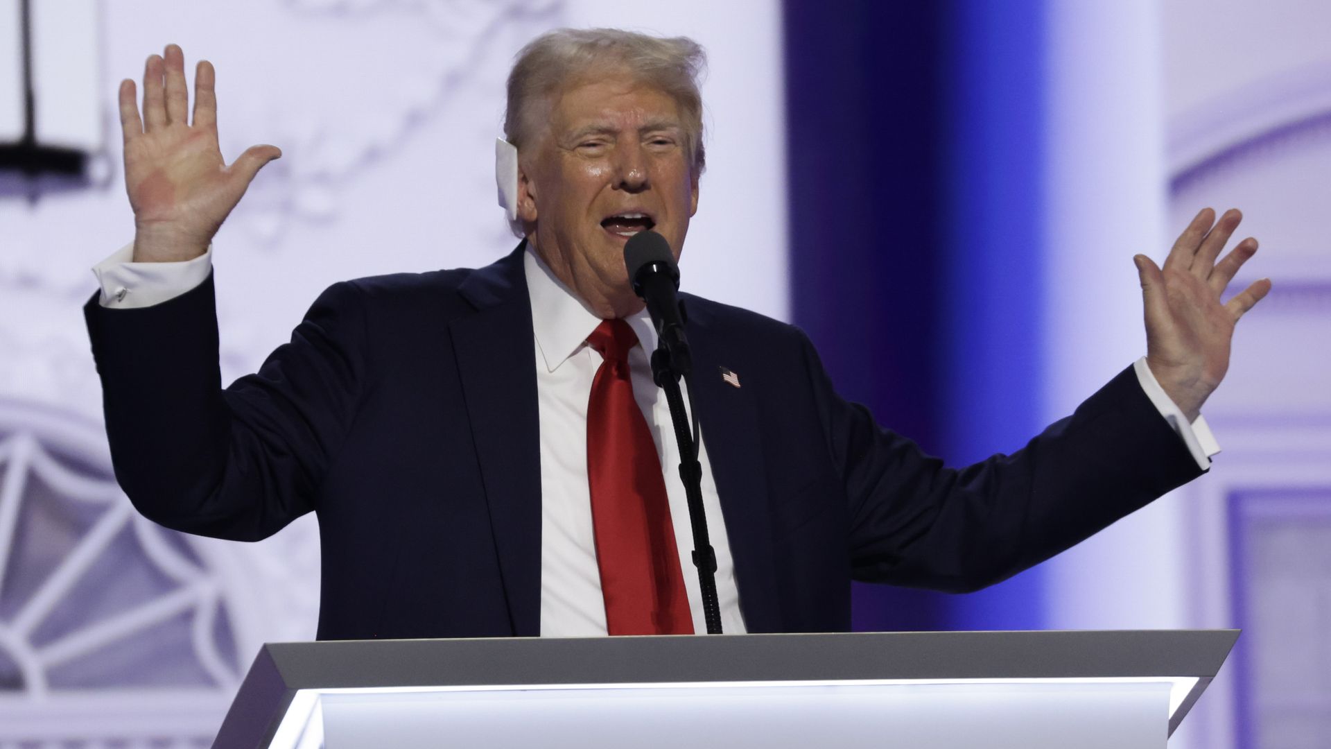 Donald Trump speaks into a mic with his hands raised