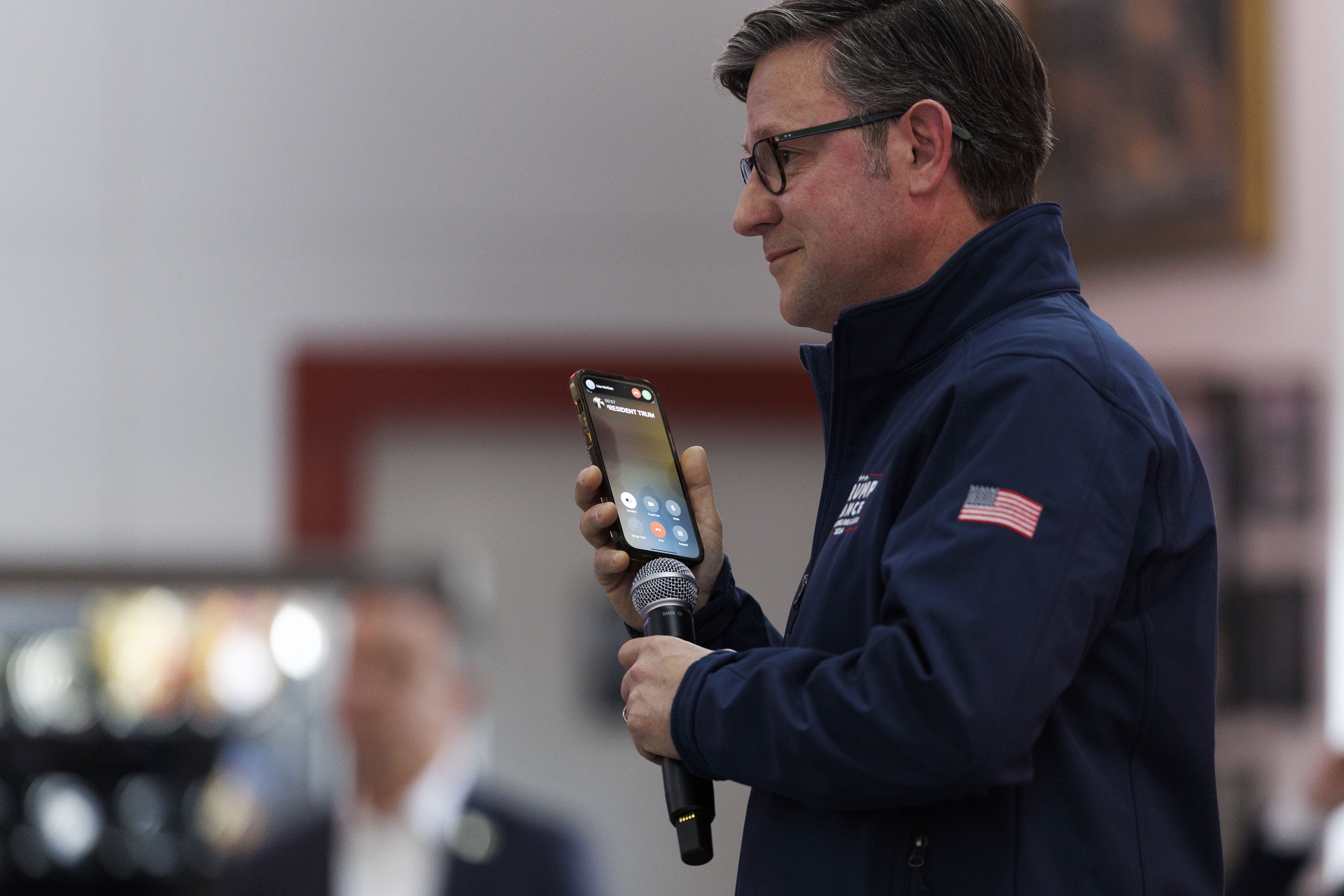 Speaker Mike Johnson holds his phone to a microphone so President Trump can speak to a campaign rally for candidate Matt Van Epps in Franklin, Tenn., yesterday.