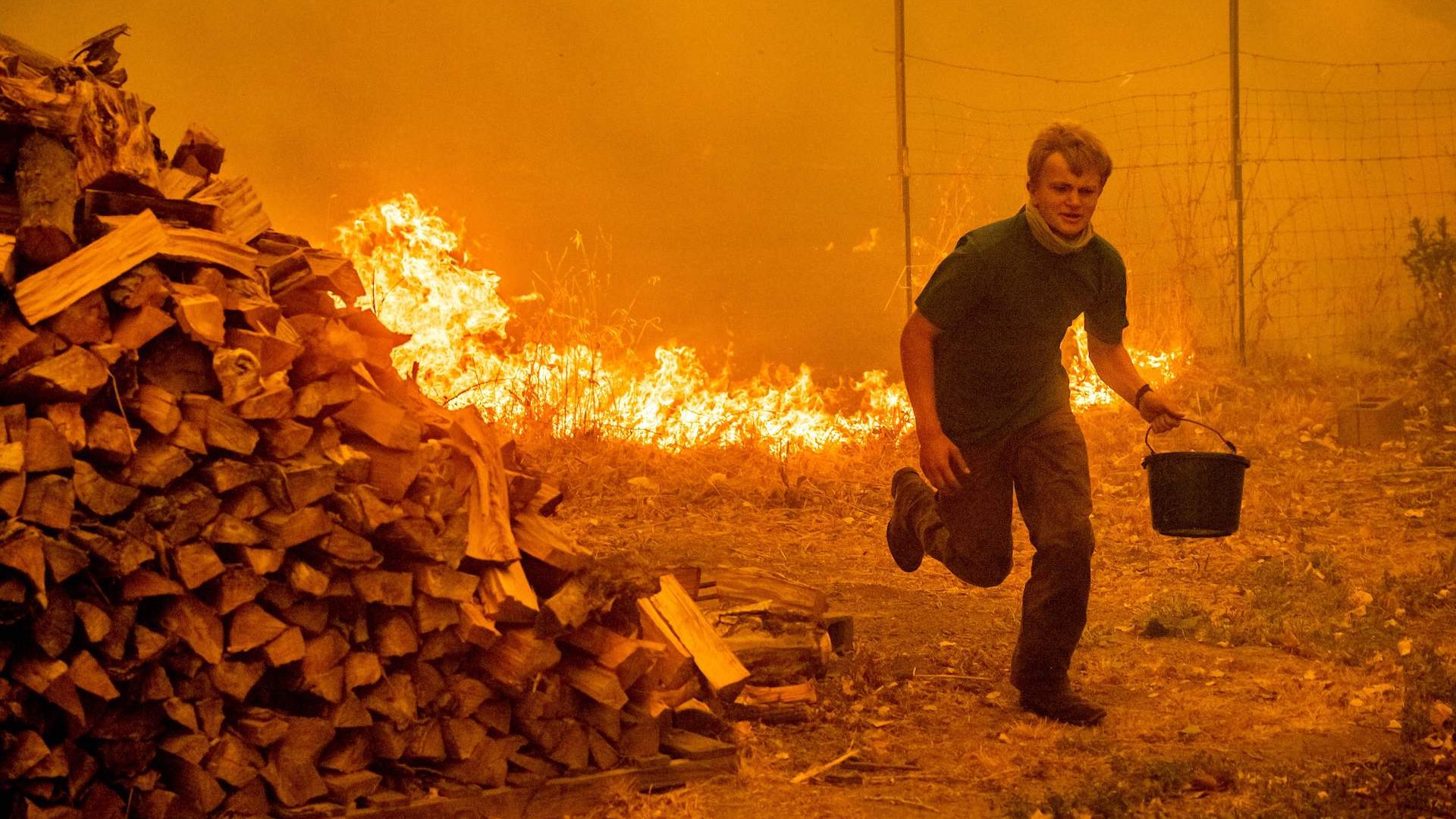Alex Schenck carries a water bucket while fighting to save his home as the Ranch Fire tears down Clearlake Oaks, California, on August 4, 2018.