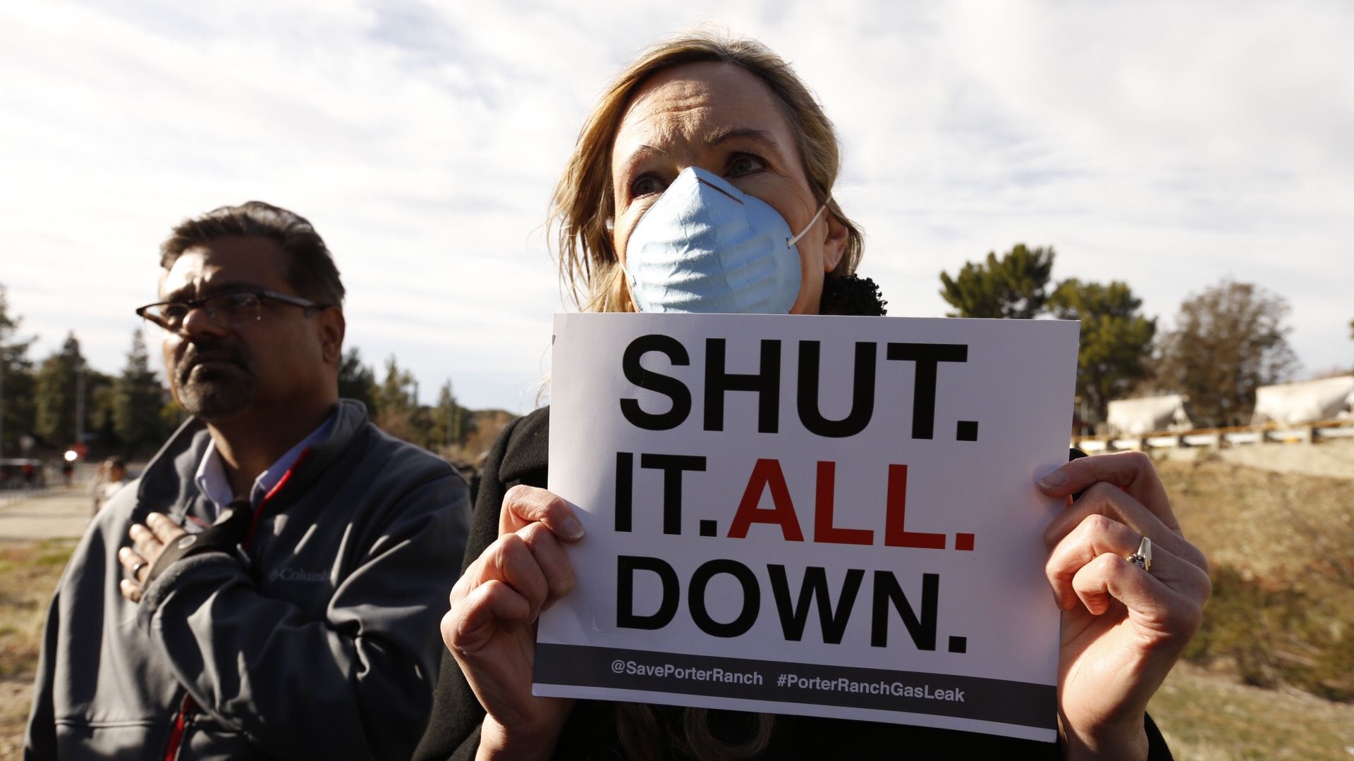 An evacuee with Save Porter Ranch holds a sign to "shut it all down" outside Southern California Gas Company's Aliso Canyon gate in Porter Ranch over the continuing gas leak in 2016 