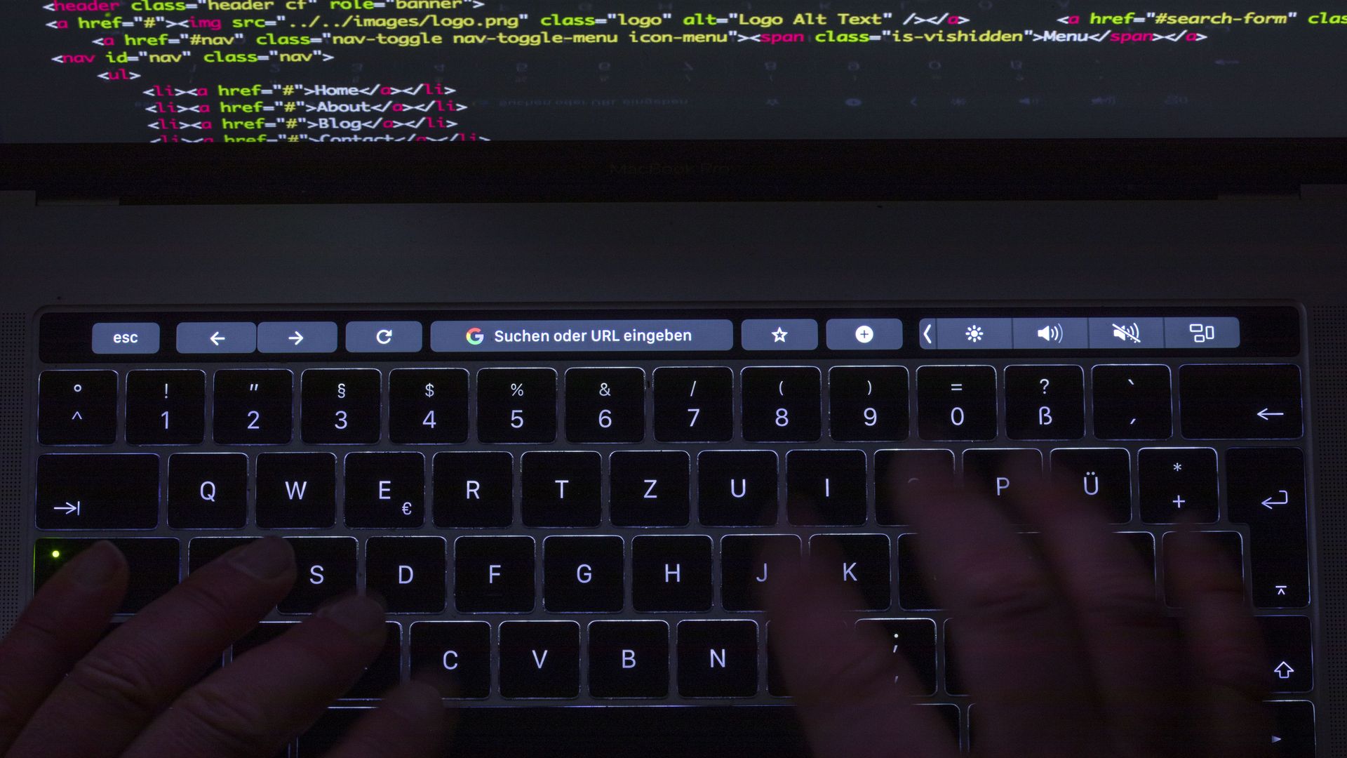 Photo of hands typing computer code on a laptop keyboard.