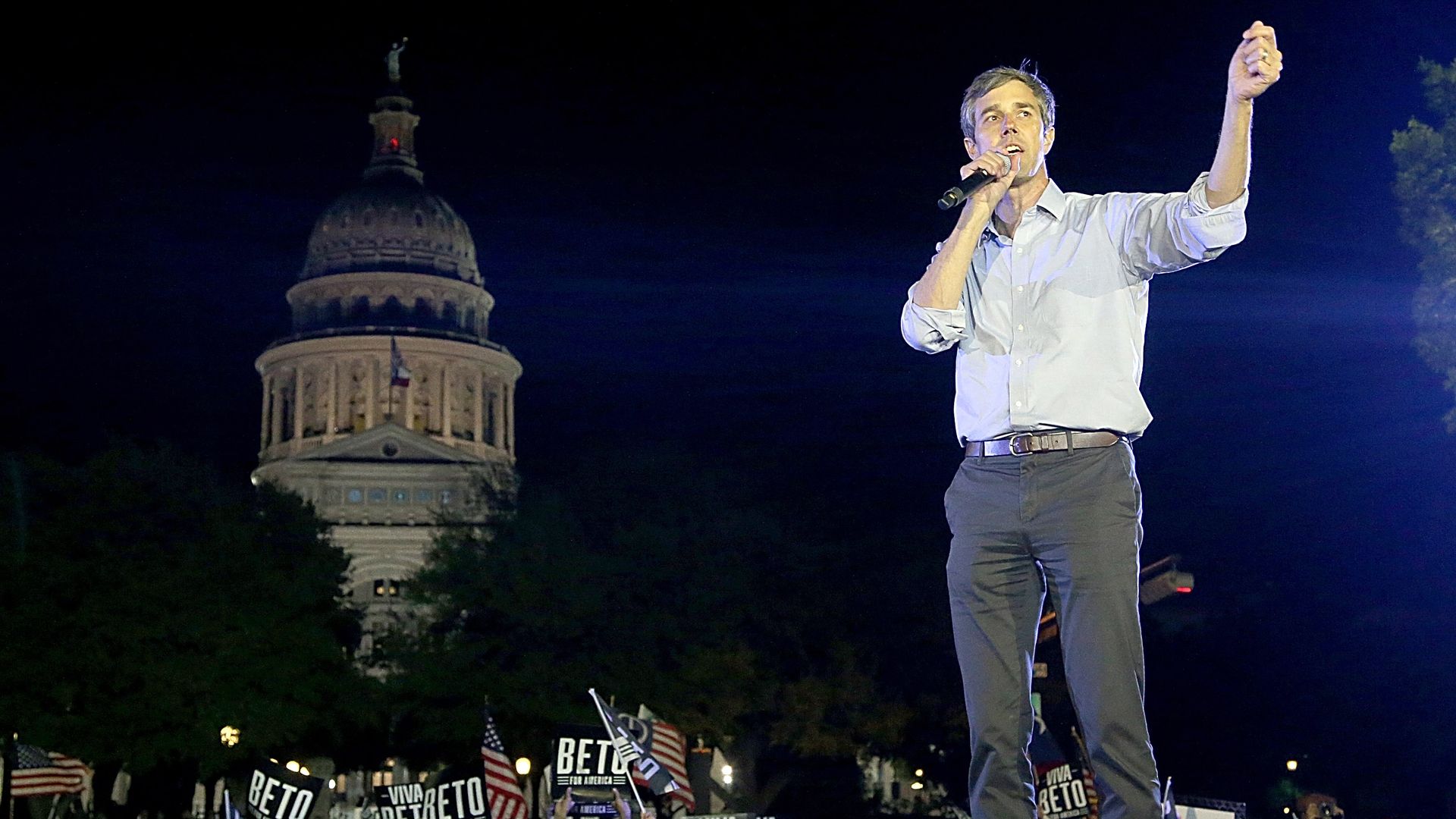A photo of Beto O'Rourke standing on a stage with a crowd and the Texas Capitol in the background.