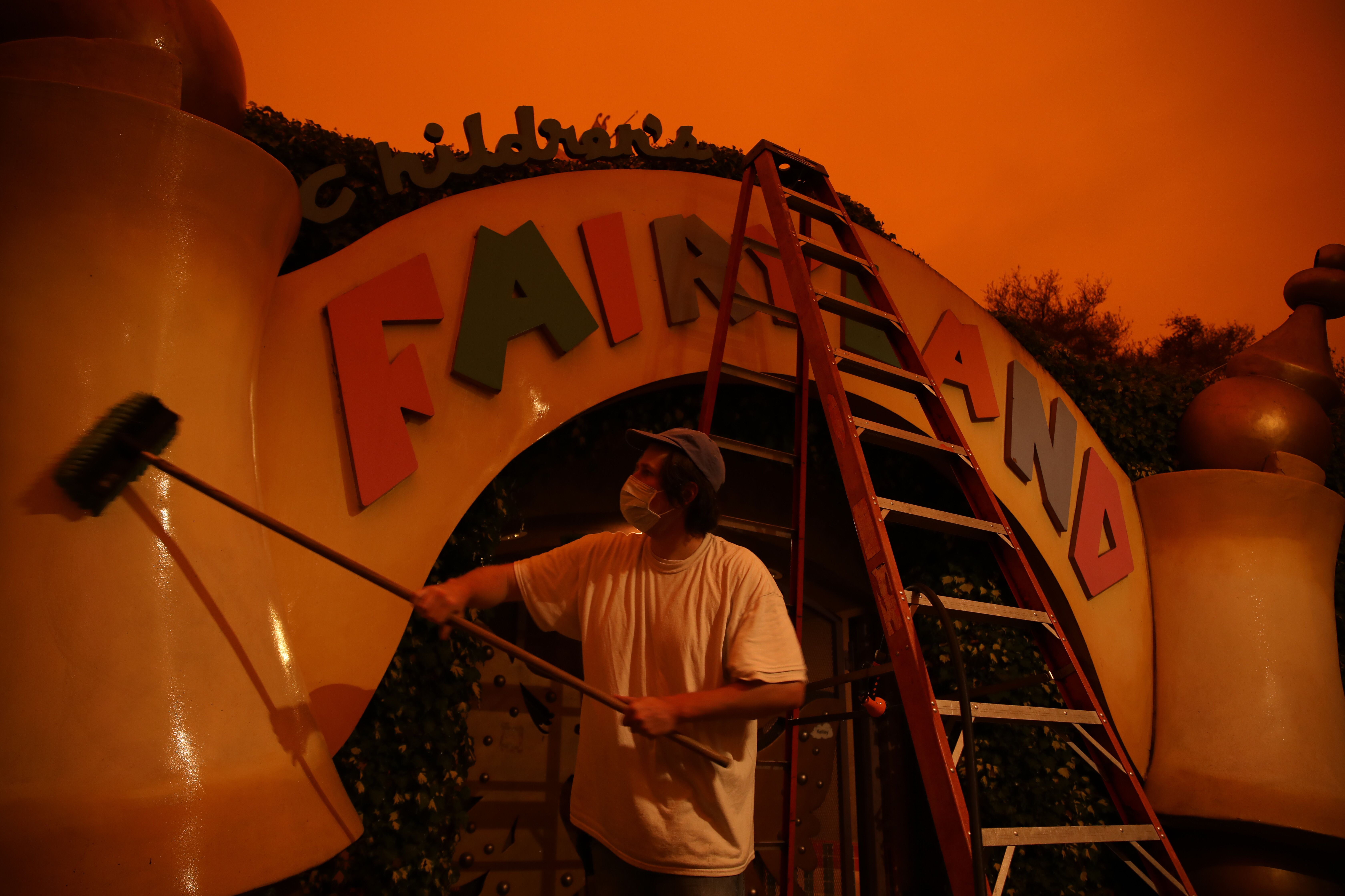A man holds a long brush against the front entrance of "Fairyland" 