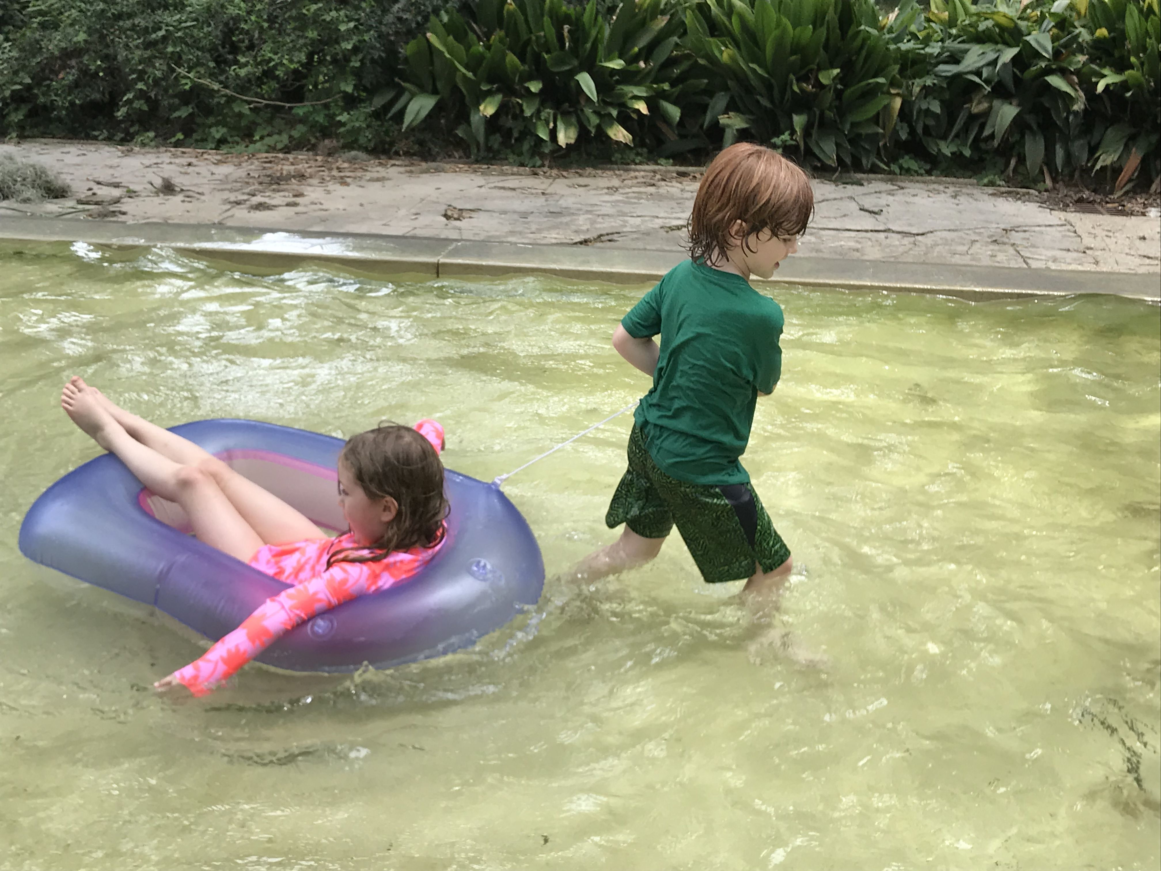 Photo shows two children playing in a wading pool.